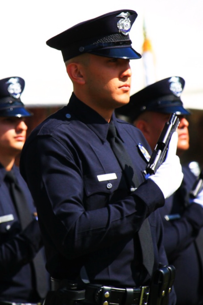 Police officers in uniform holding guns during a formal event.
