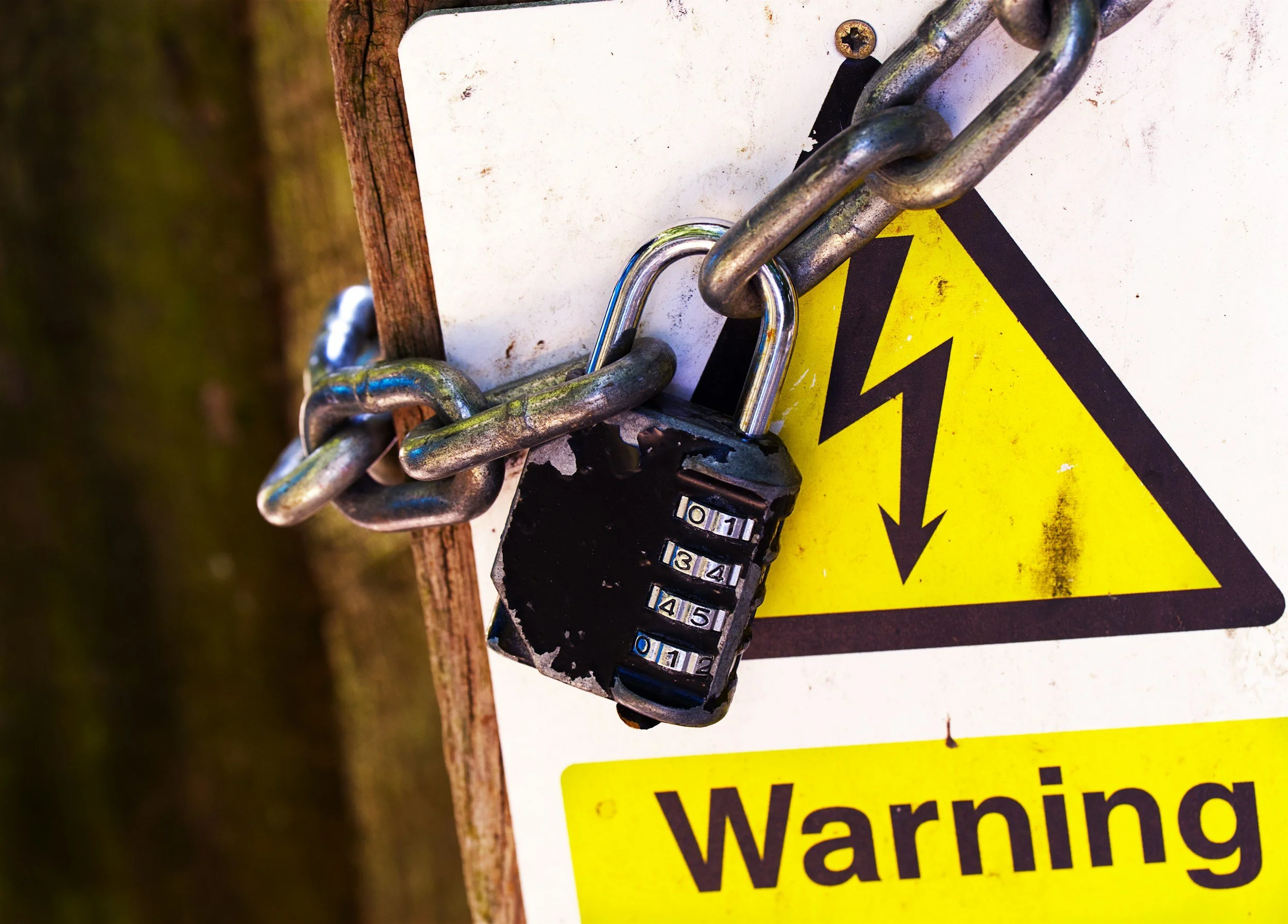 Cadenas de seguridad con candado y un cartel de advertencia en color amarillo con letras negras