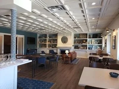 Modern lounge area with multiple seating options, built-in wall shelves with decor, and a ceiling with recessed lighting.