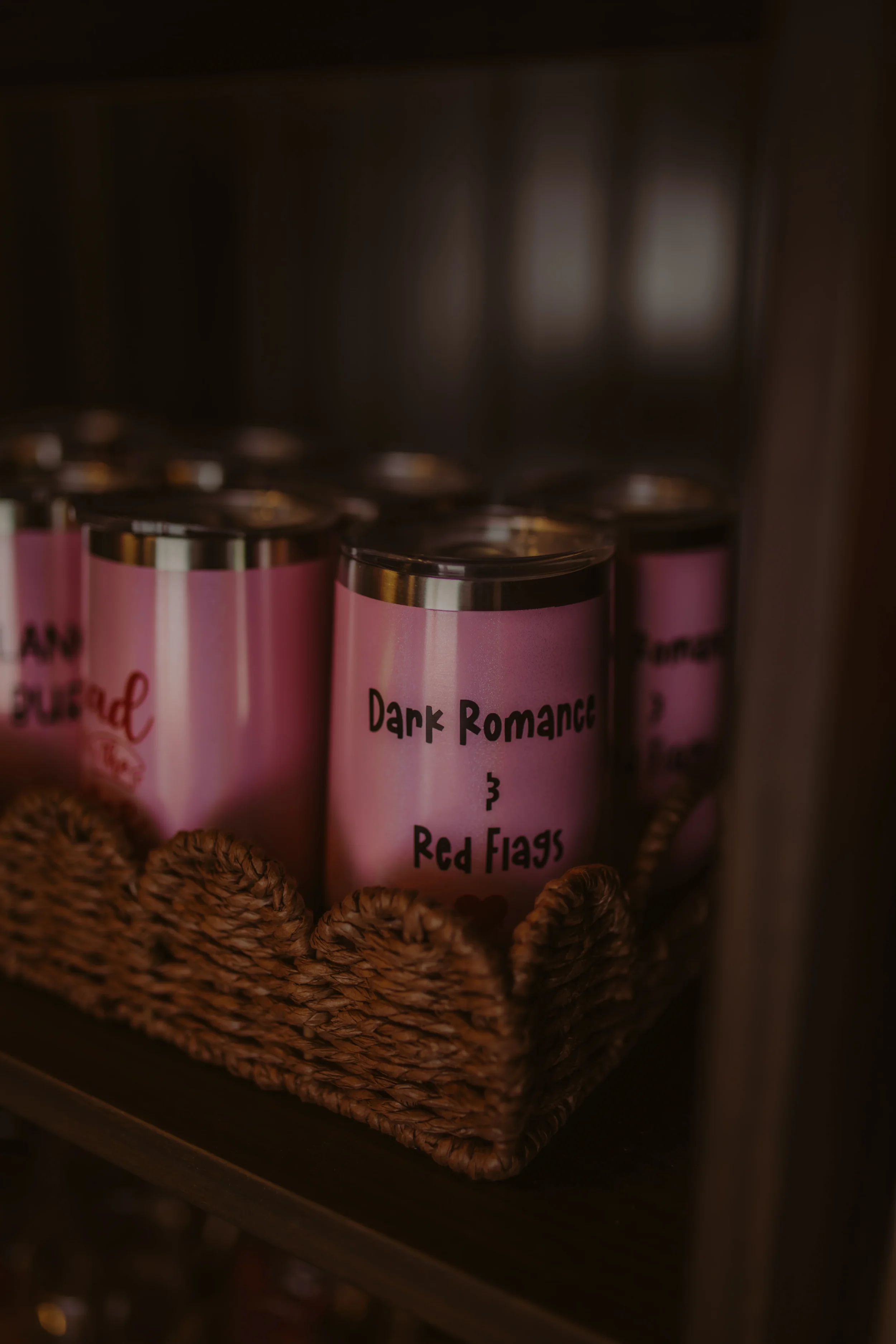 Close-up of a labeled candle in a basket. The label reads 'Dark Romance 3 Red Flags.'