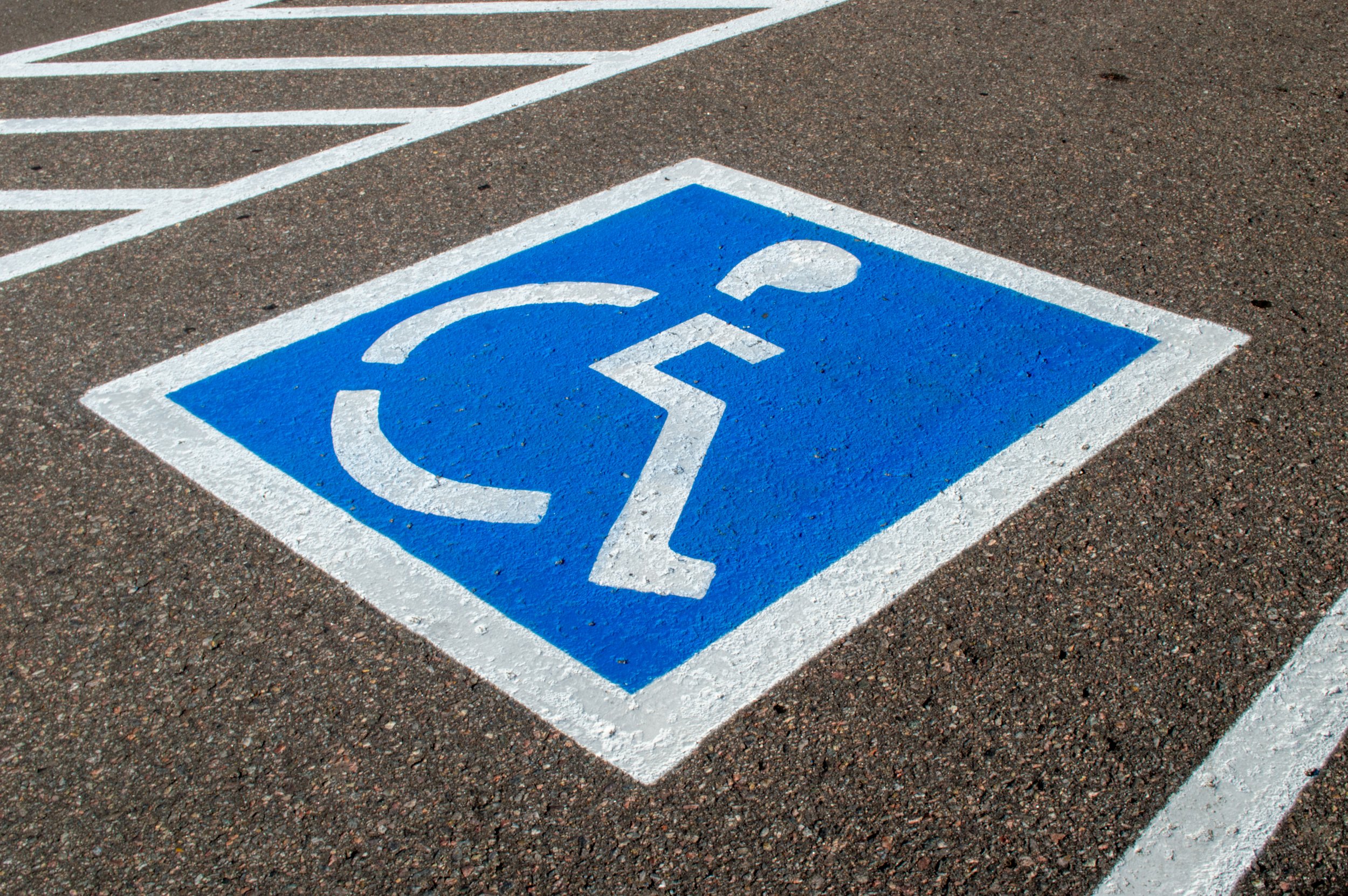 Crisp Blue and white painted parking space marked for handicapped accessible parking on asphalt pavement.