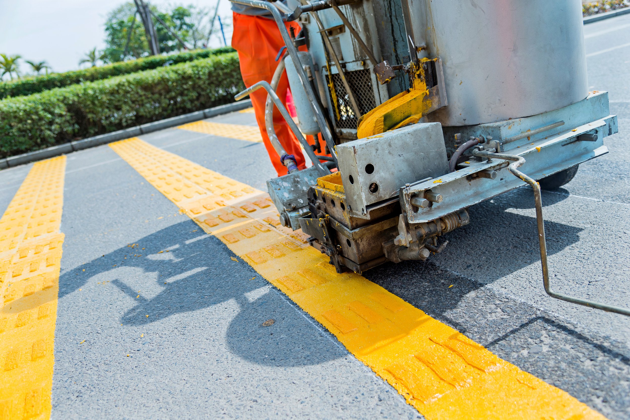 Painting yellow lines and textured markings on the asphalt road to create a pedestrian crosswalk.