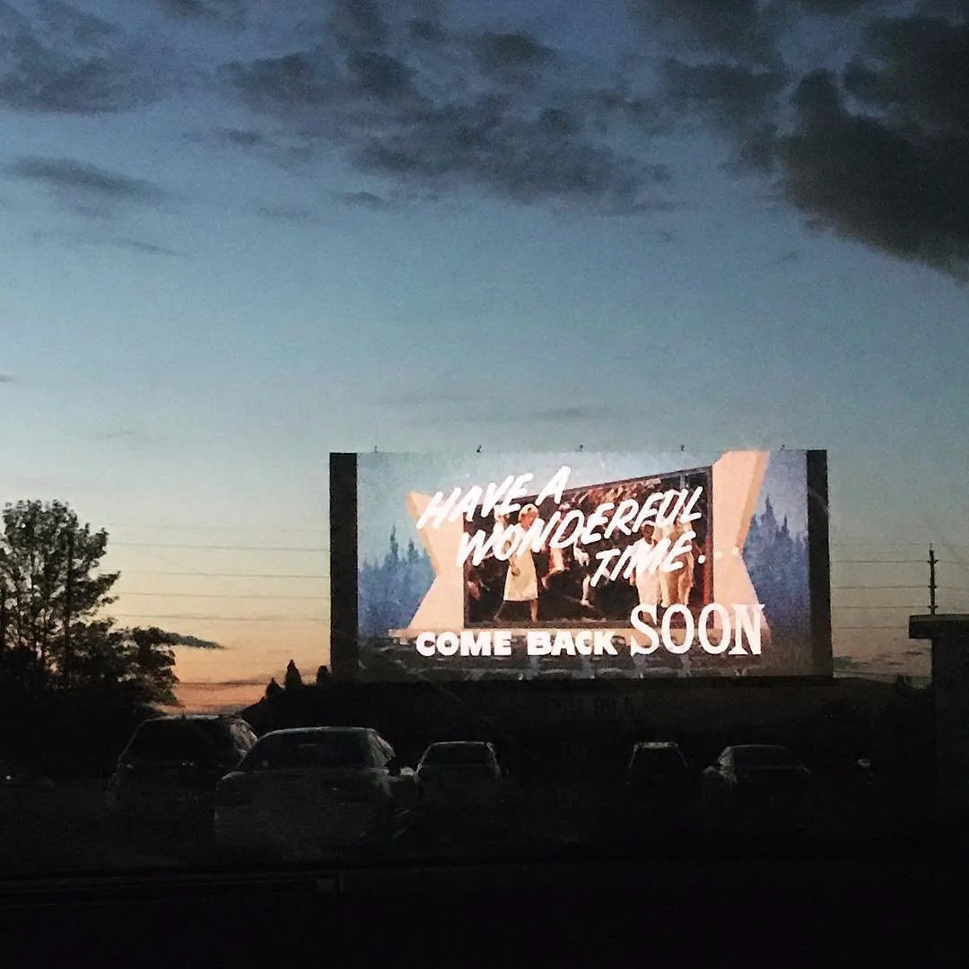 Photo of Stardust drive-in theatre in Sharon, East Gwillibury, ON. Photo features a dark parking lot with a screen that says "Have a wonderful tie. Come back soon/"