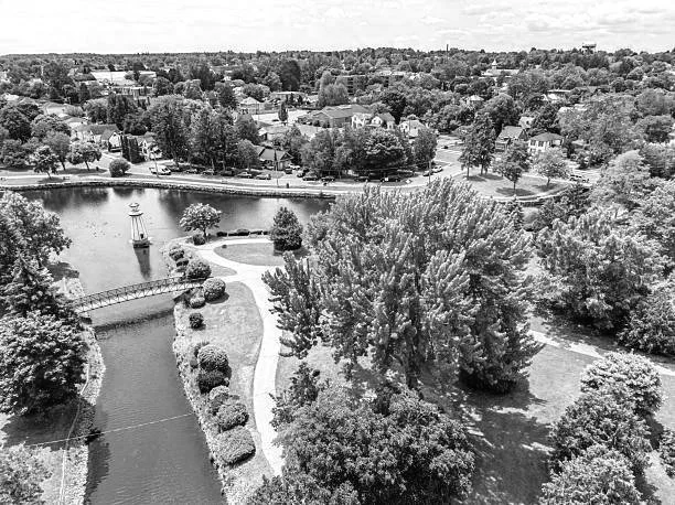 Aerial view of a park with a pond, walking paths, trees, and surrounding neighborhood houses.