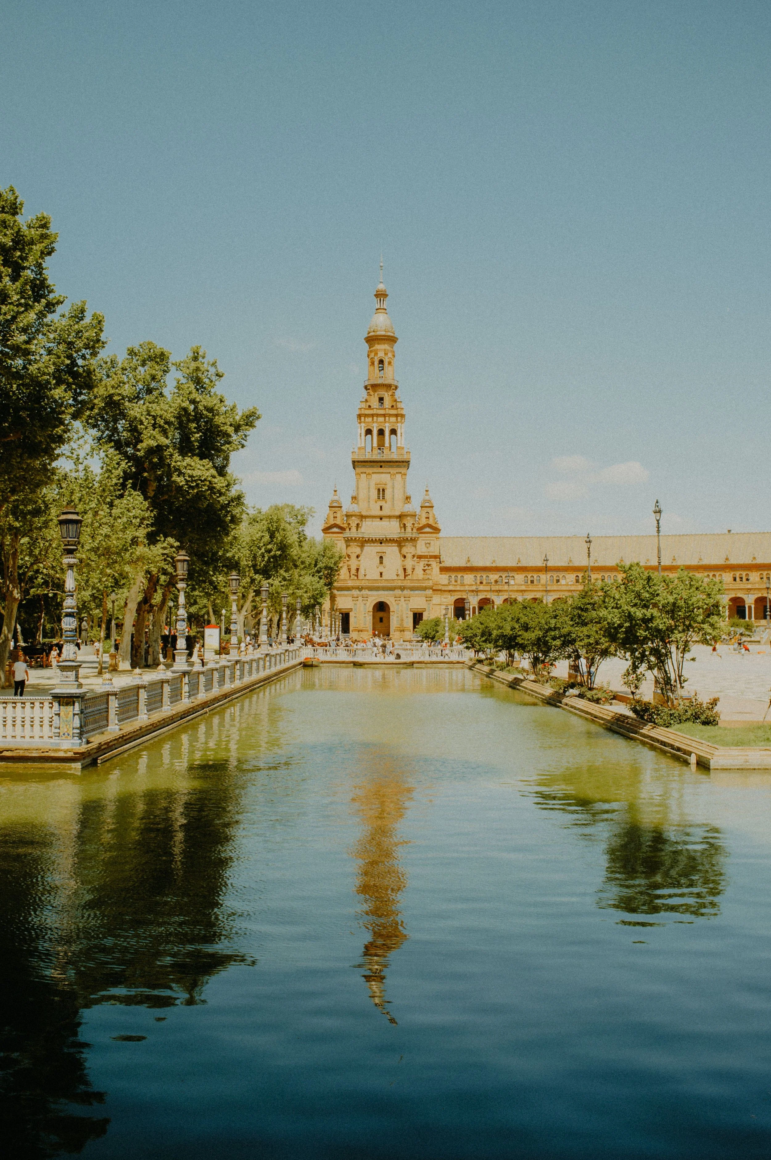 Reflective canal and grand pavilion tower at Plaza de España in Seville, Spain.