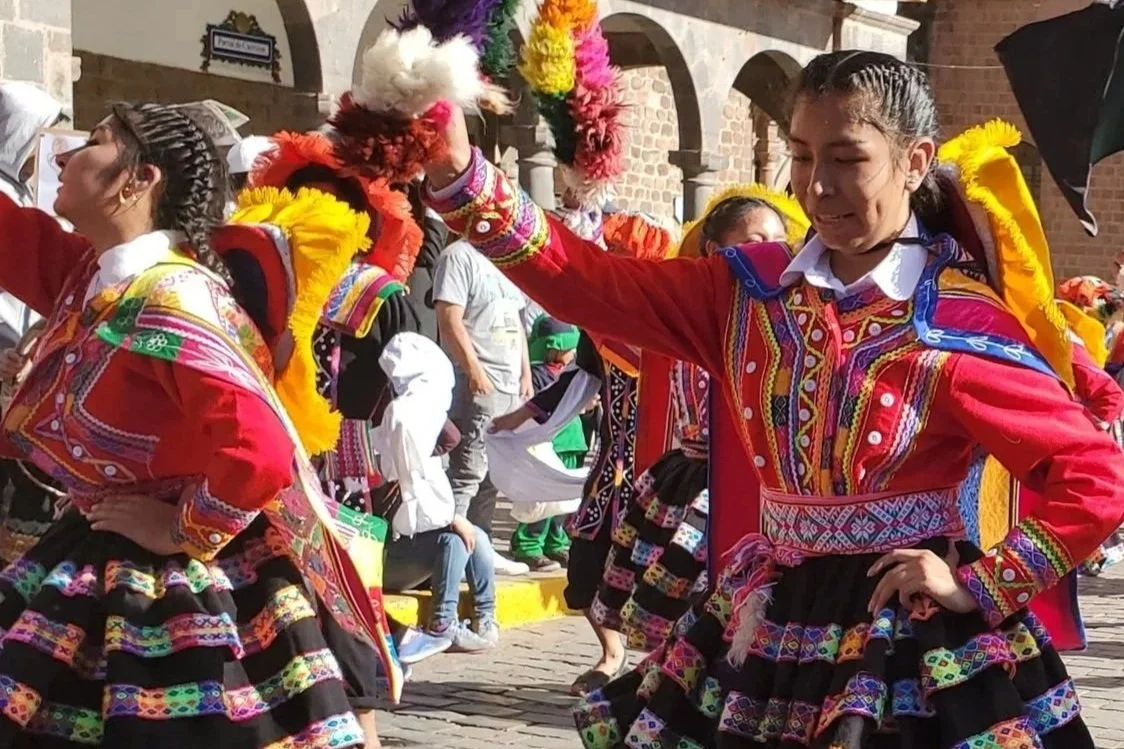 Experiencing the vibrant Fiesta de las Cruces in Cusco, Peru on May 4th as folkloric dancers perform in colorfully embroidered traditional dresses.