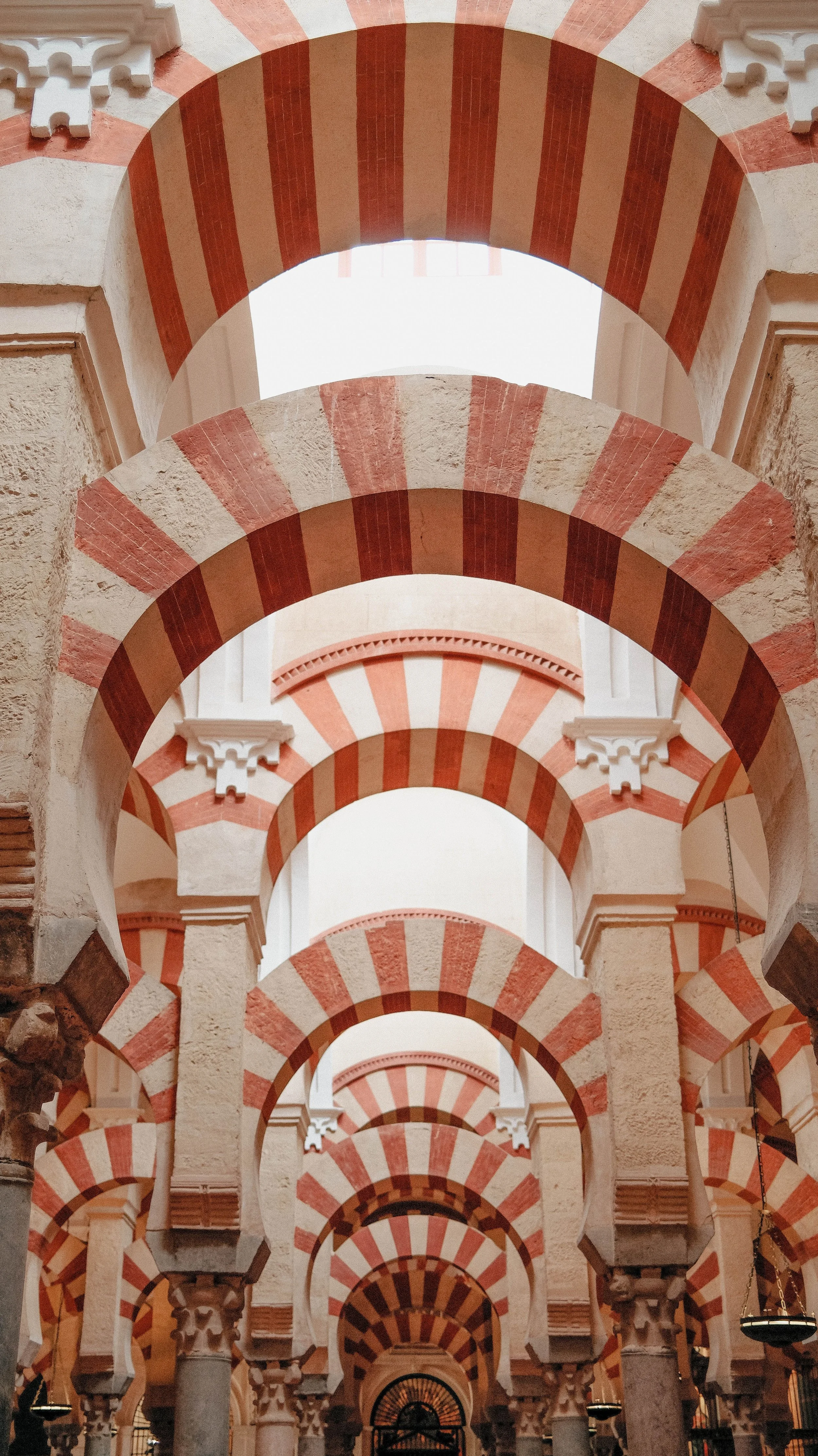 Iconic red and white striped double arches inside the historic Mosque-Cathedral of Córdoba, Spain.