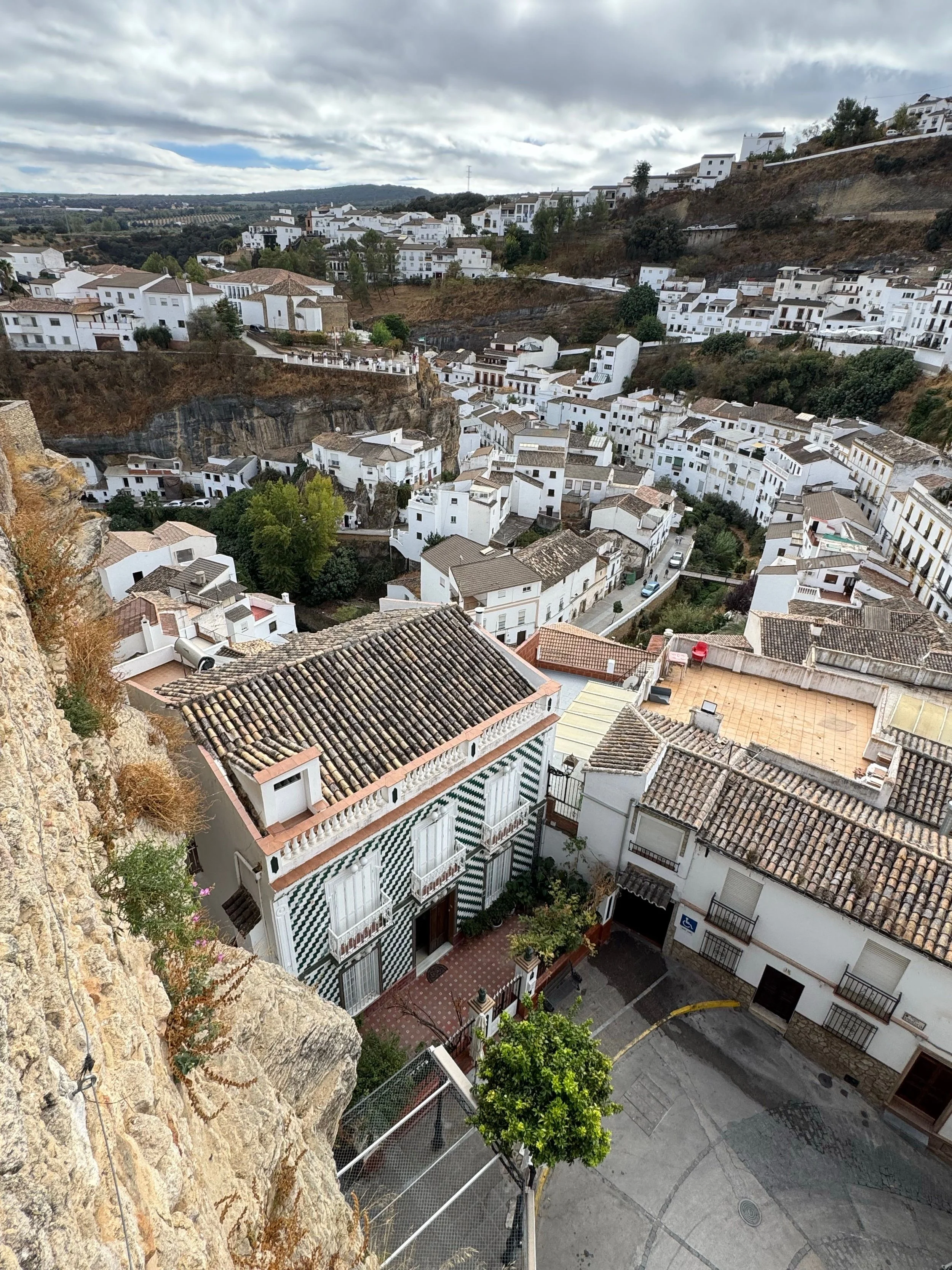 Traditional white-washed buildings nestled along the steep rocky cliffside of Ronda, Spain.