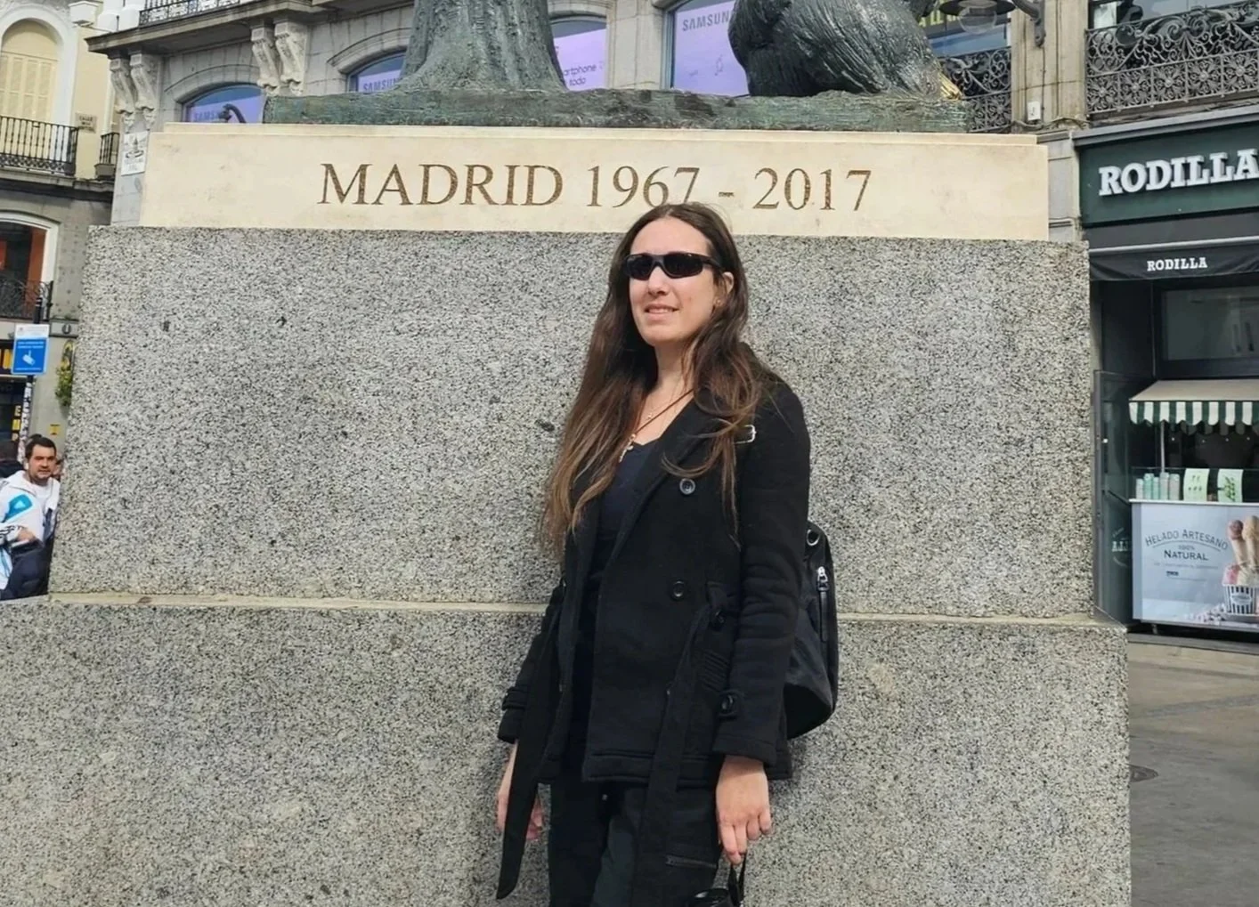Wendy exploring the vibrant historic streets of Madrid, standing before the iconic Madrid city monument.