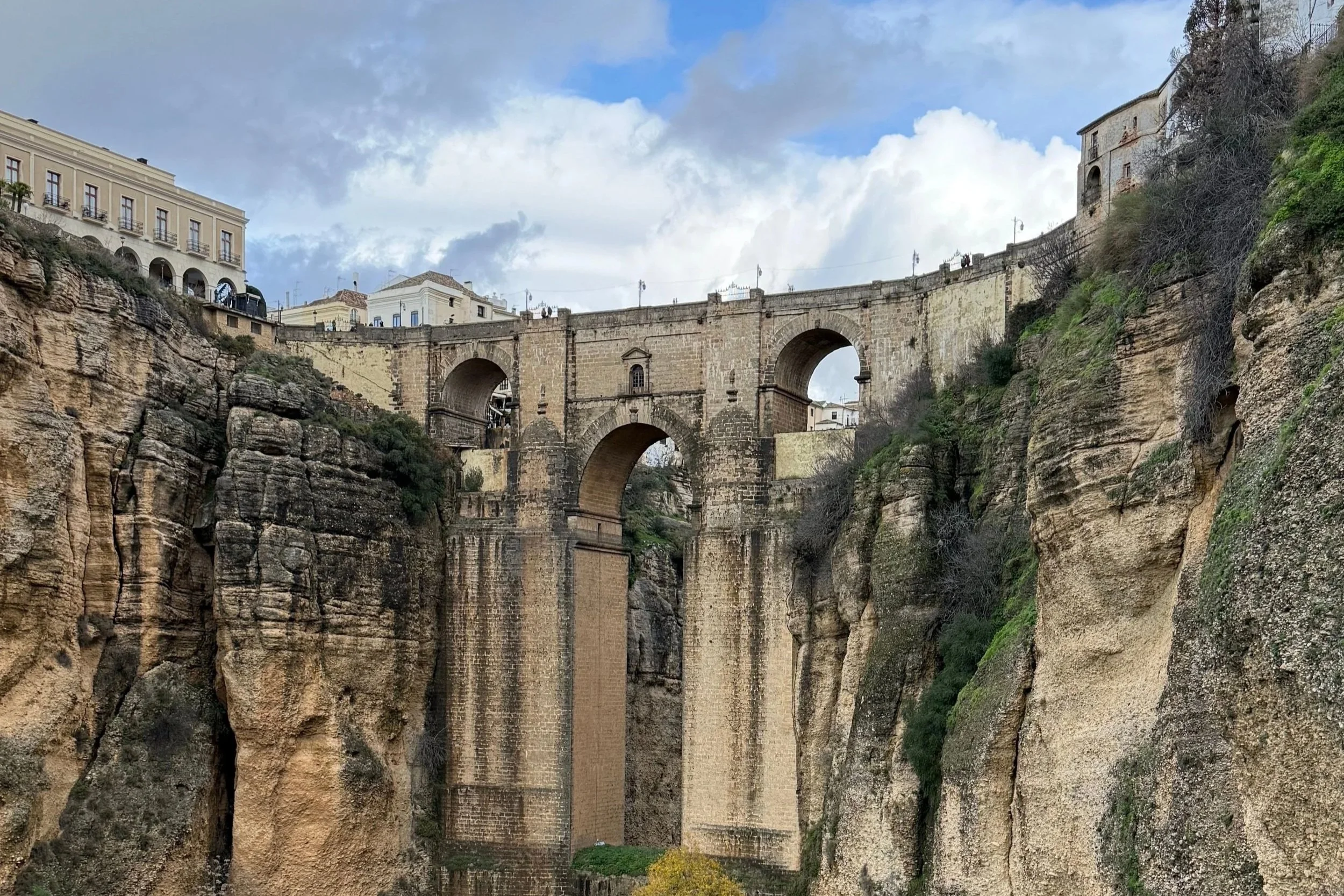 Marveling at the dramatic stone arch bridge spanning a deep rocky gorge in historic Ronda, Spain.