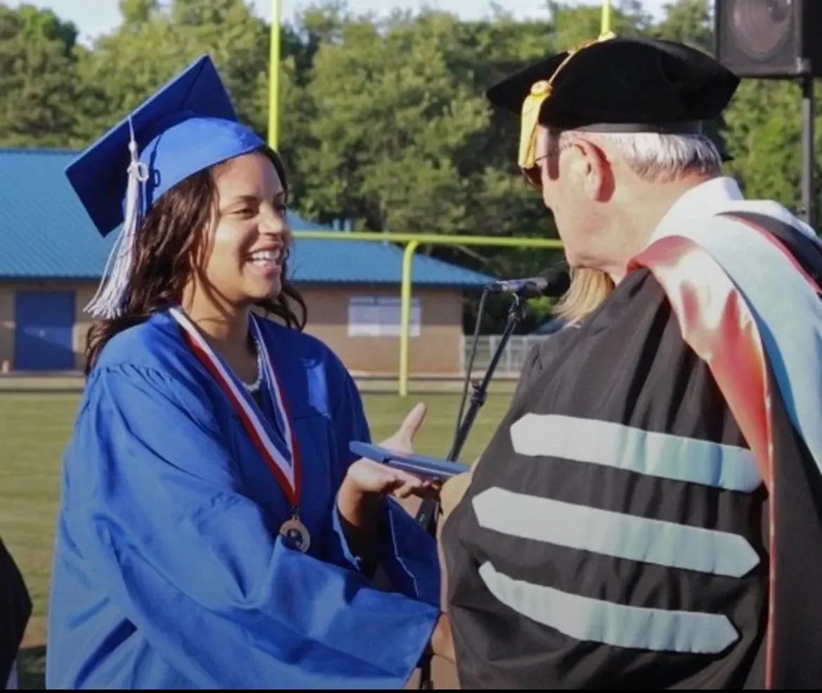 Dr. Brenda in a blue cap&gown at a graduation ceremony