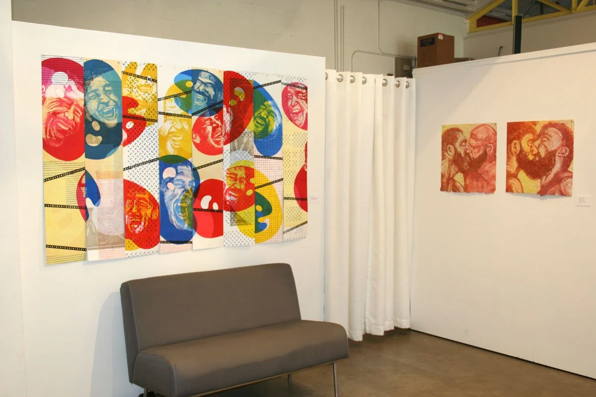 Colorful pop art paintings of people laughing and smiling displayed on gallery walls, with a gray sofa in front. One large multi-panel artwork on the left and two smaller pieces on the right.