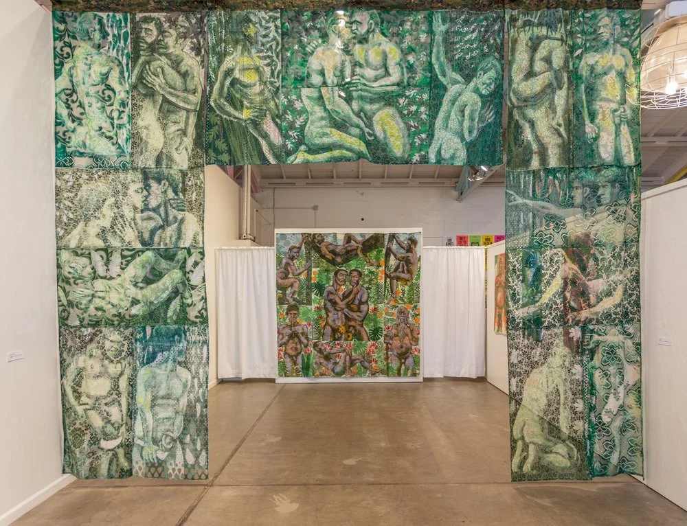 An art installation consisting of a large, rectangular archway made of hanging fabric panels with painted or printed images of Ndebele-style patterns and figures, leading into a room with additional artwork featuring similar styles and themes.