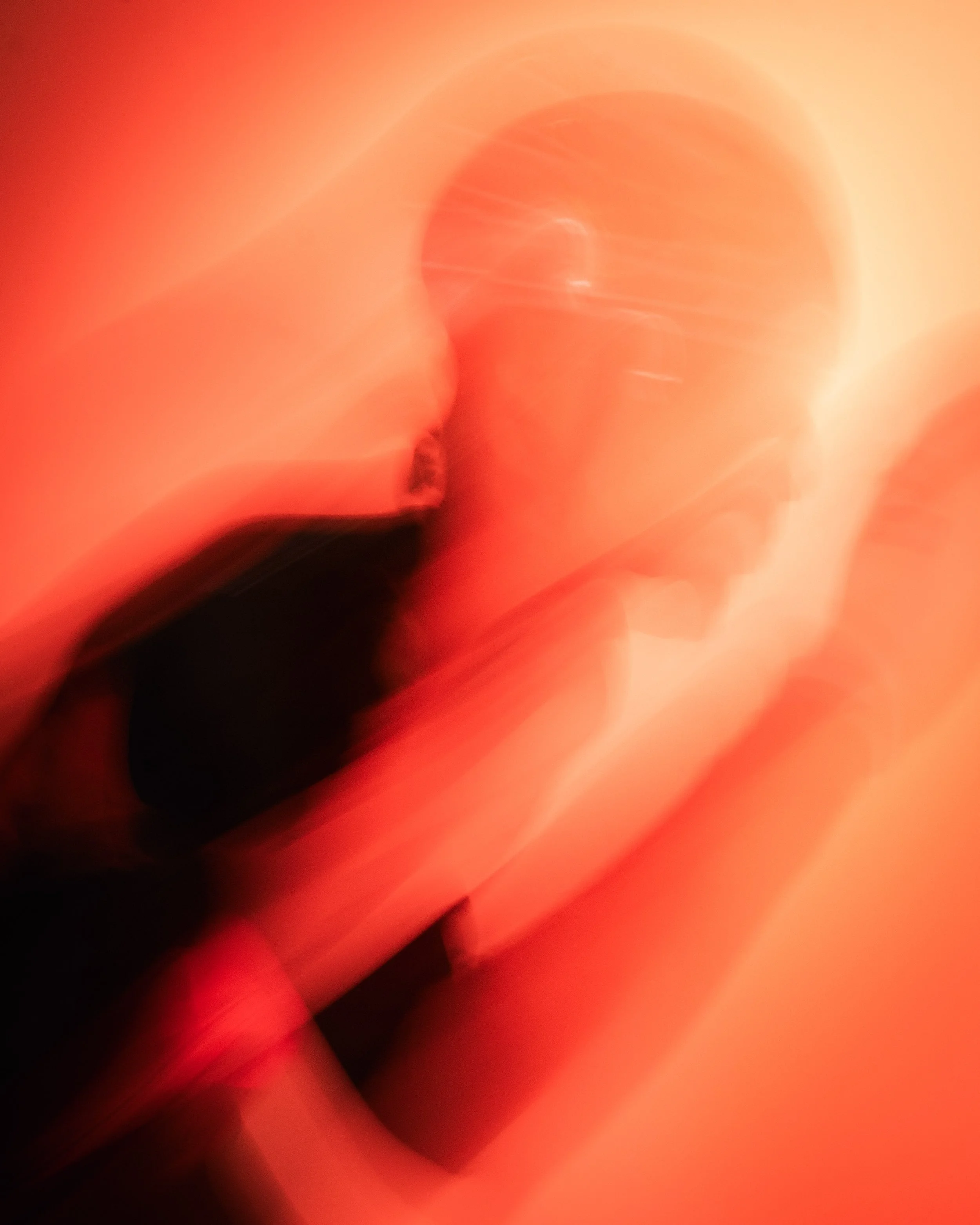 Blurred abstract image with warm red, orange, and yellow colors, showing streaks and light patterns.