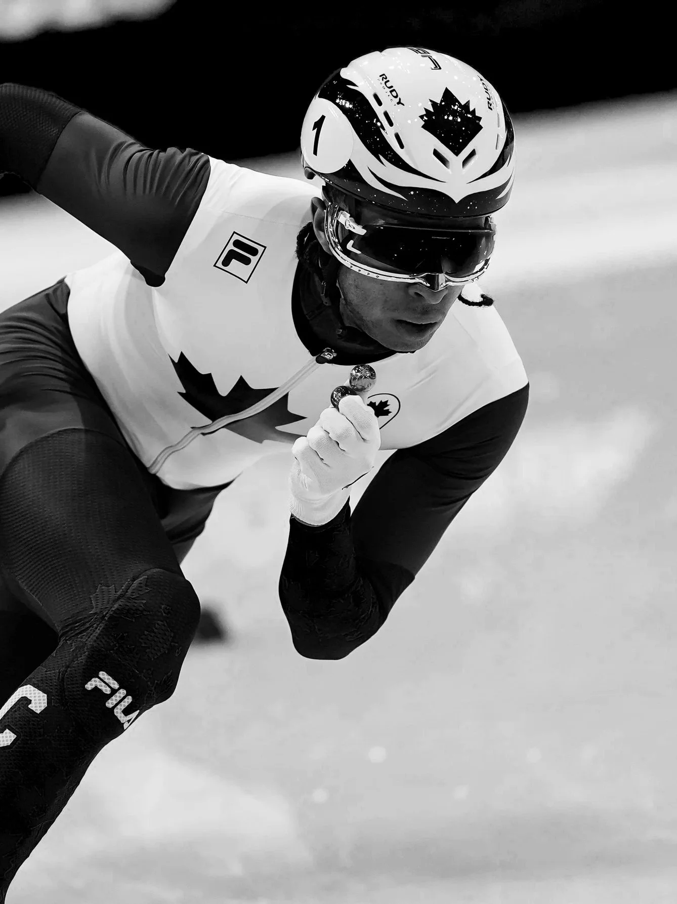 A male athlete in a cycling outfit and helmet, crouching on a race track, likely during a competitive event.