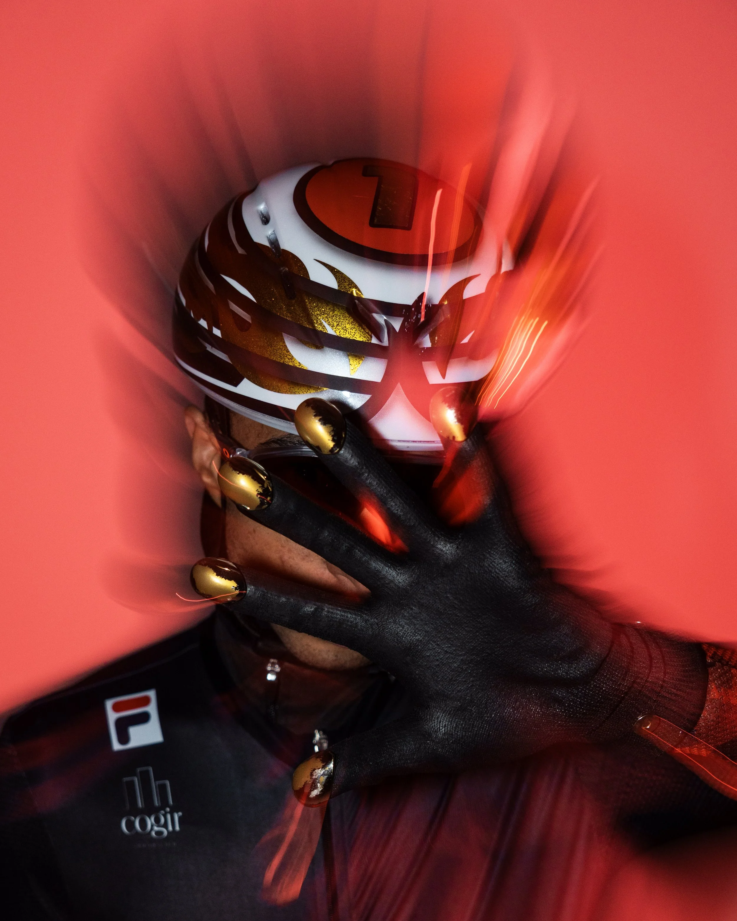 A person wearing a white, black, and gold helmet with a red visor and golden accents, holding a black object, surrounded by red light effects.
