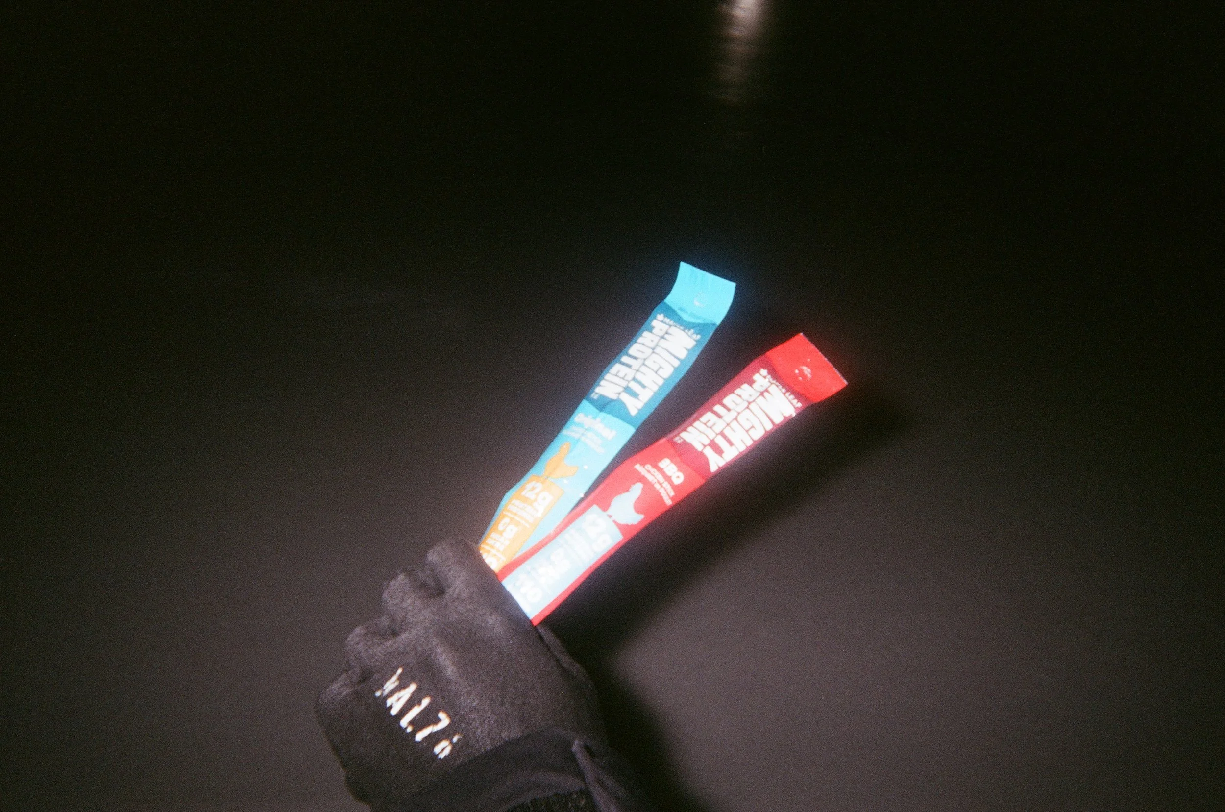 A person's feet wearing black sneakers standing in front of colorful greeting card banners on a dark surface.