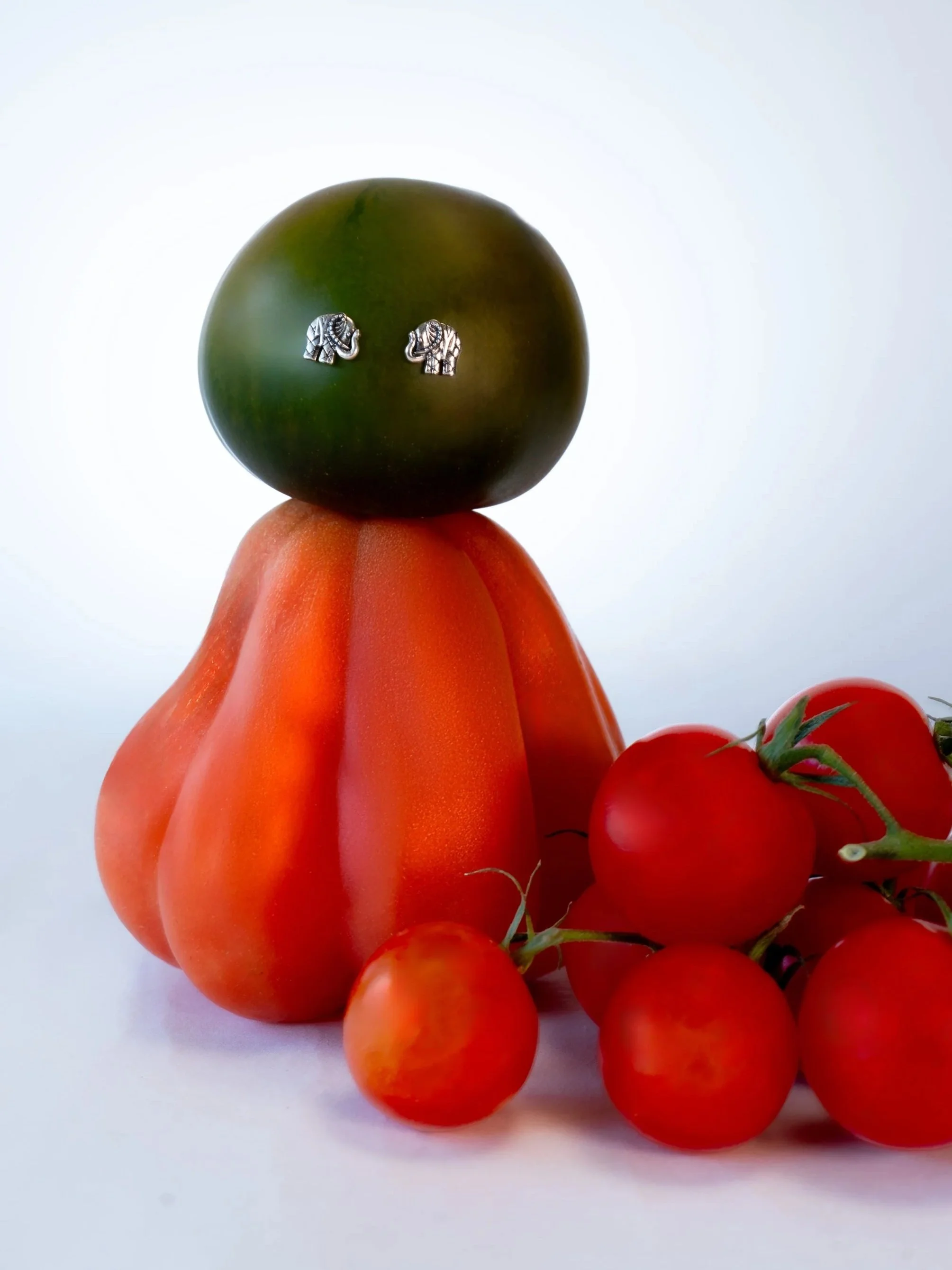 Verschiedene Tomaten, darunter rote, grüne und orangefarbene, auf weißem Hintergrund.