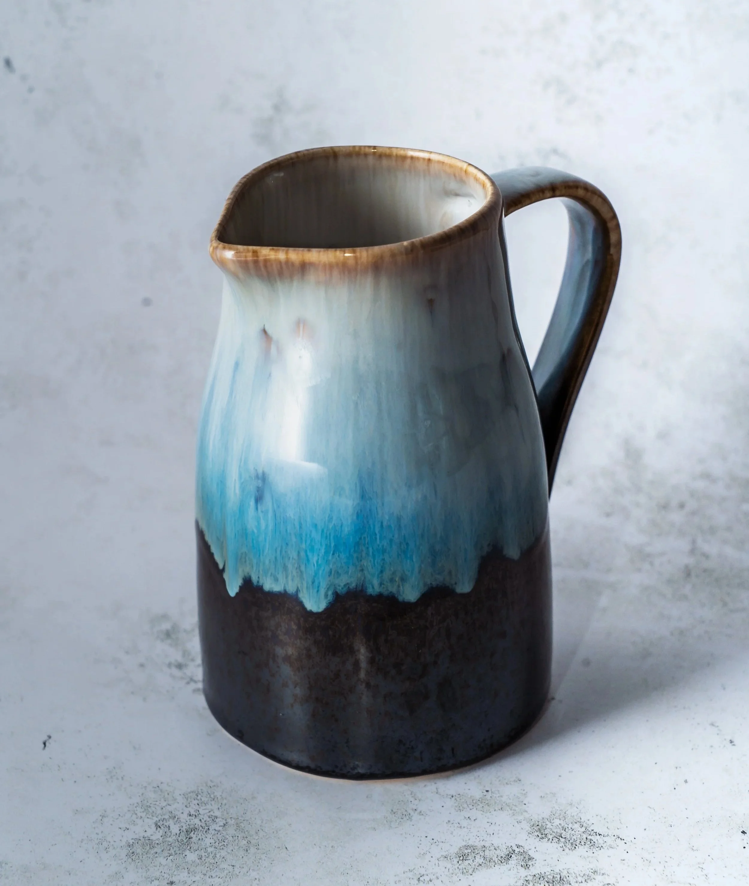 Eine Tasse mit blau-weißem Farbmuster, auf einem grauen Untergrund.