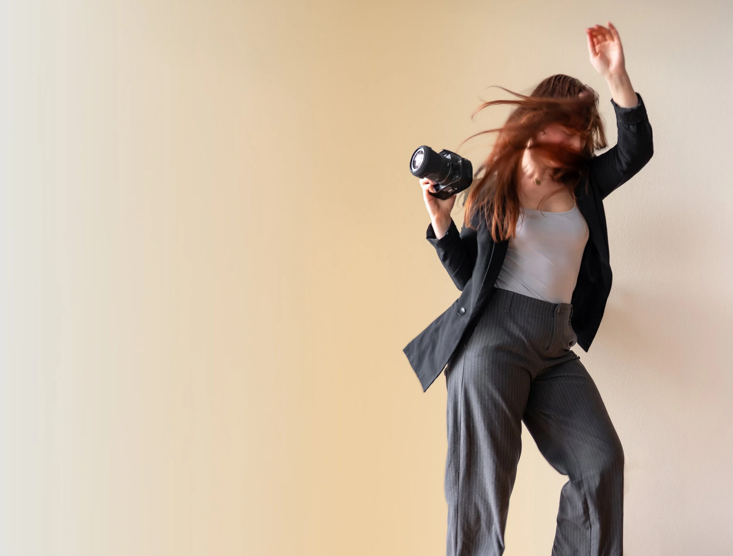 Frau tanzt mit einem Filmprojektor in der Hand vor einer hellen Wand.