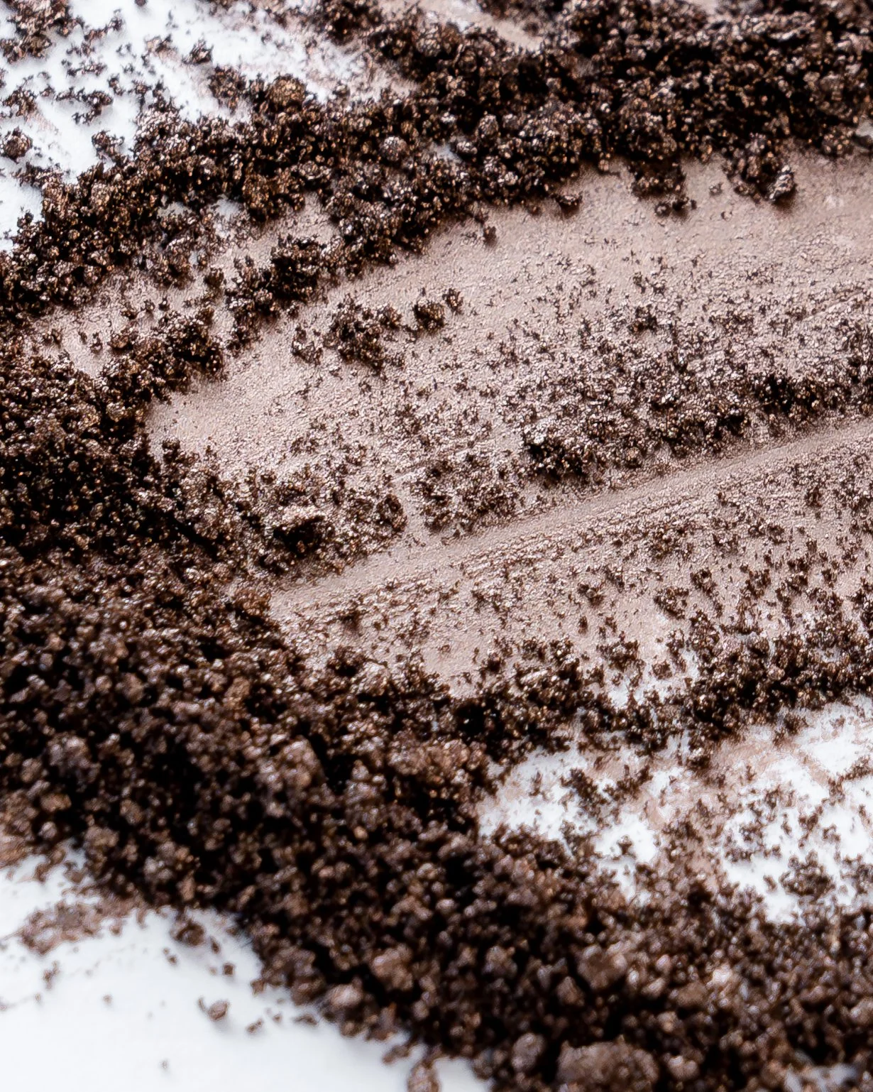 Nahaufnahme von zerstoßener Kaffeebohne auf einer weißen Oberfläche.