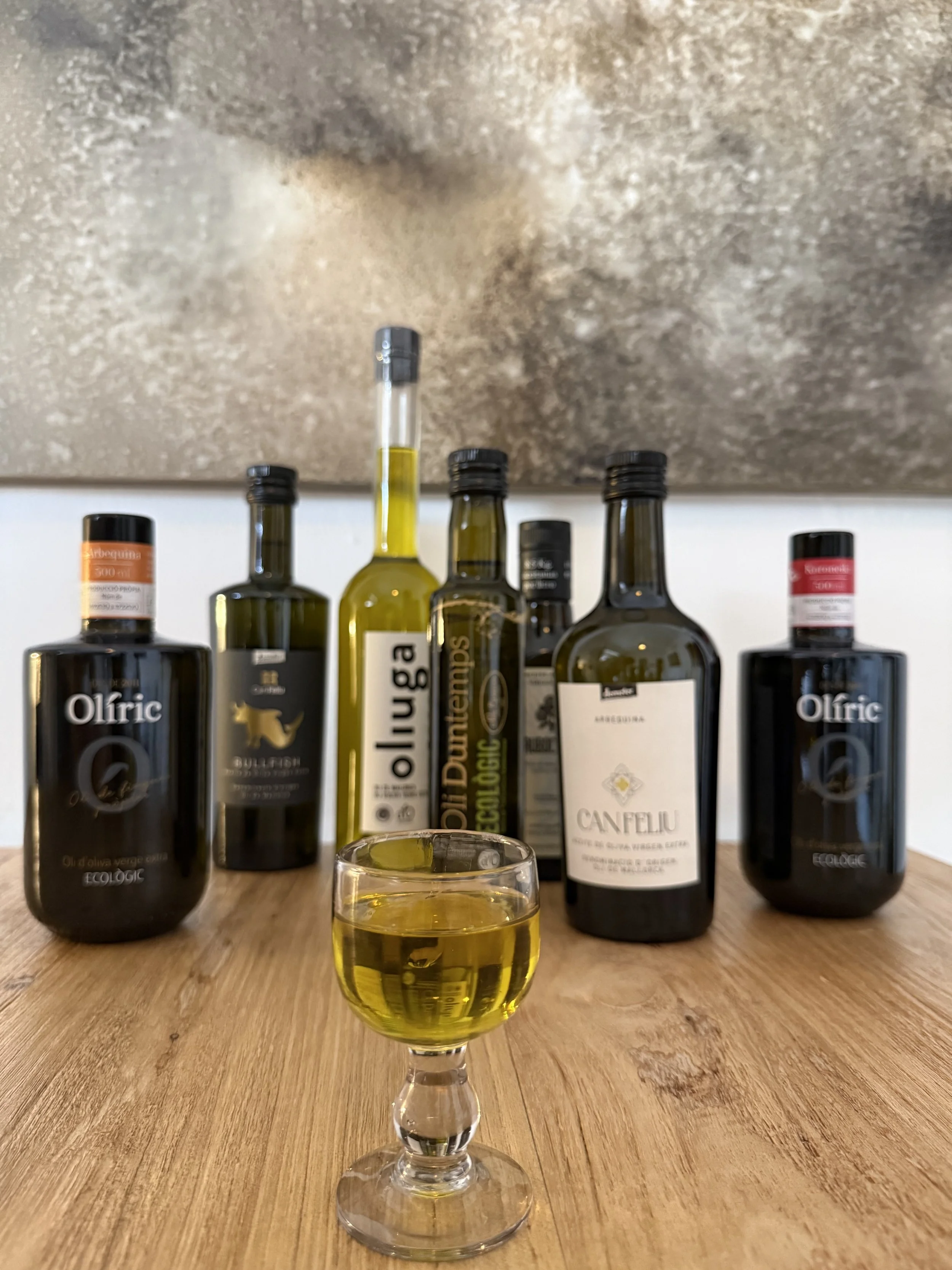 Glass of golden Mallorcan extra virgin olive oil and bottles at an EVOO tasting and pairing experience in Palma's historic center.