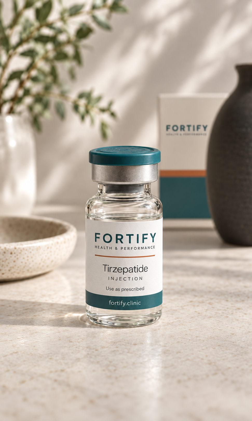 A small glass vial labeled 'Fortify,' containing Tirzepatide injection, on a light-colored surface with decorative vases and a box in the background.