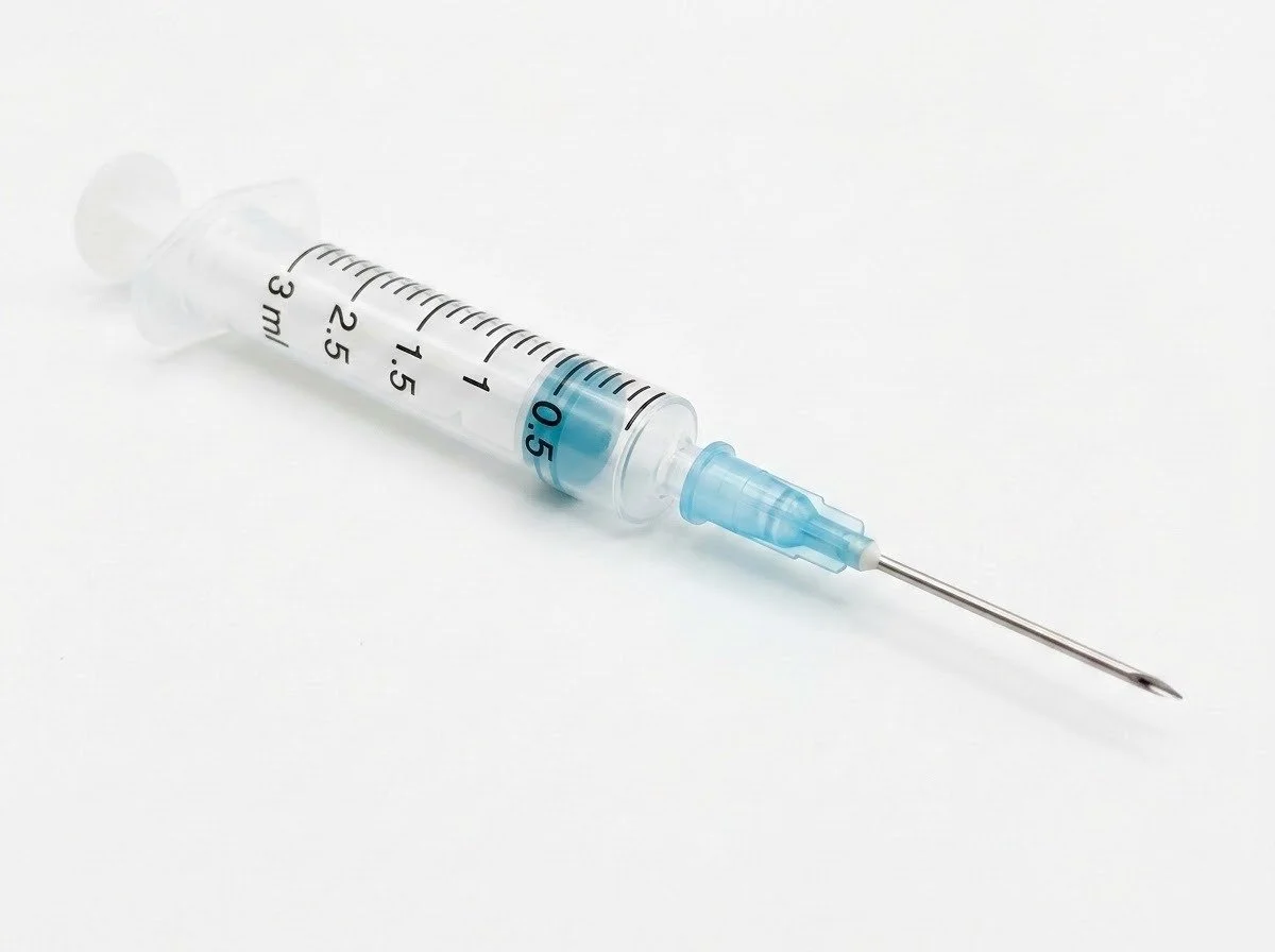 A medical syringe with a needle, filled with clear liquid, on a white background.