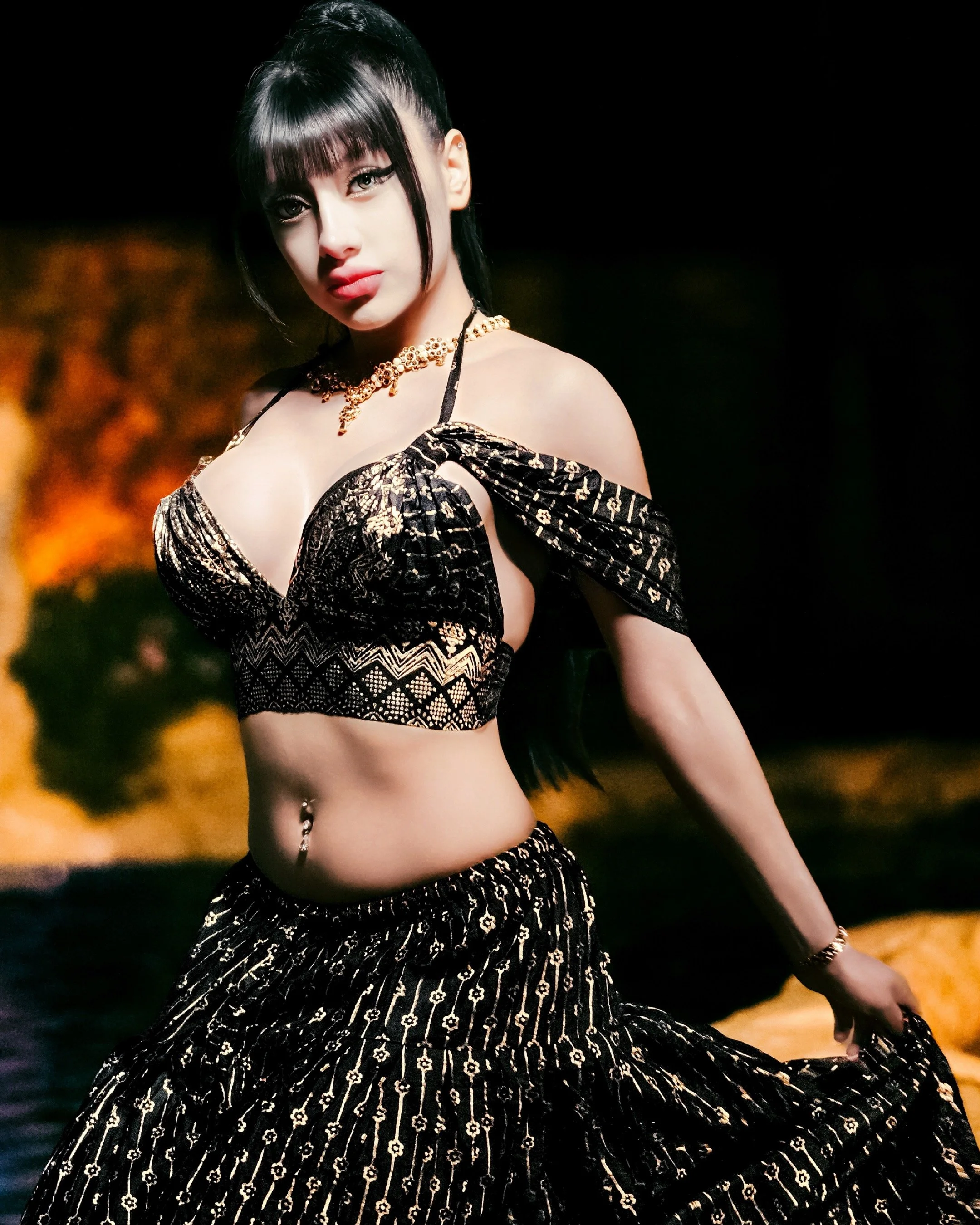 A woman with dark hair and makeup, wearing a black and gold patterned outfit with a cutout design, jewelry including a gold necklace and earrings, standing outdoors at night with blurred warm lighting in the background.