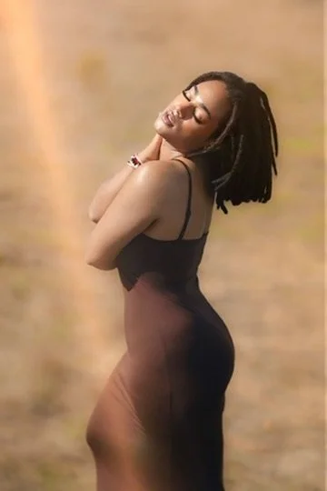 A woman with dreadlocks posing outdoors with her eyes closed, wearing a black dress.Photographer, for hire, Oceanside, Carlsbad, San Diego, Orange County, Fashion, Portraits, Moments, Lifestyle, Events, Branding.