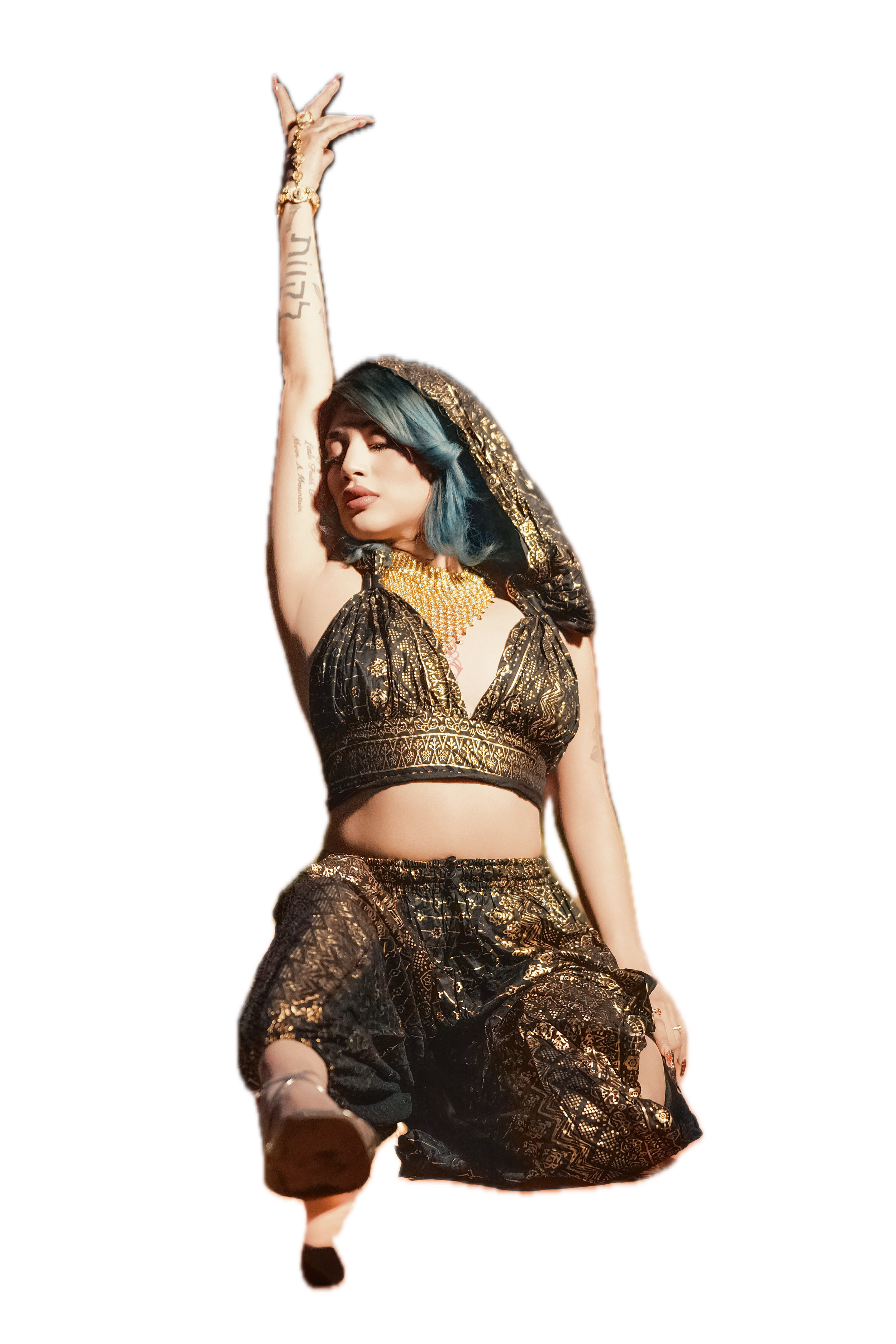 A woman with teal and black hair wearing traditional gold and black clothing, with gold jewelry, posing with one arm raised and her eyes closed against a black background.