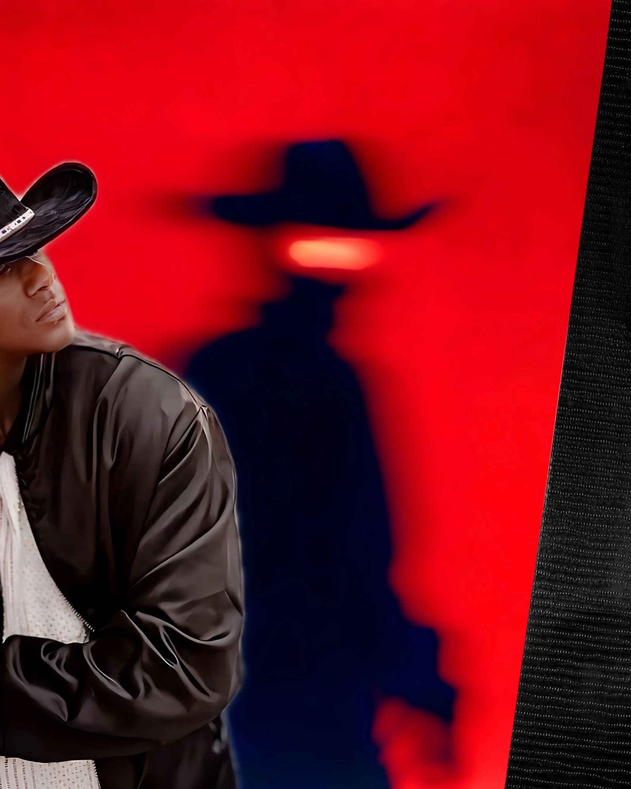 Close-up of a person wearing a black cap, black jacket, and white shirt, with a red background and a black textured surface on the right.