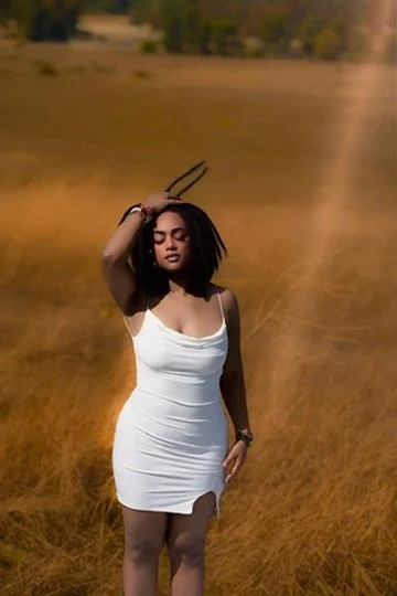 Photographer, for hire, Oceanside, Carlsbad, San Diego, Orange County, Fashion, Portraits, Moments, Lifestyle, Events, Branding.Woman in a white dress standing in a field with dry grass, holding her hand on her head.