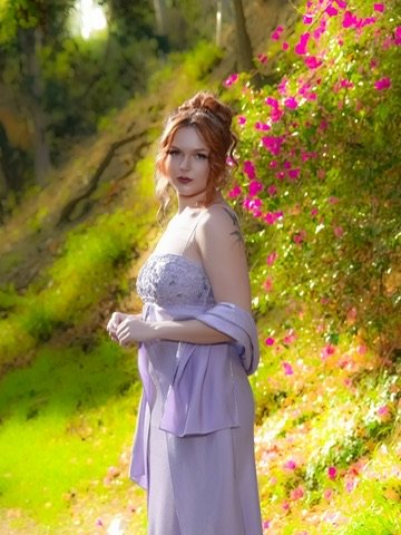 Photographer, for hire, Oceanside, Carlsbad, San Diego, Orange County, Fashion, Portraits, Moments, LA young woman with curly red hair standing outdoors near blooming pink flowers and green foliage, wearing a light purple dress and a matching jacket.