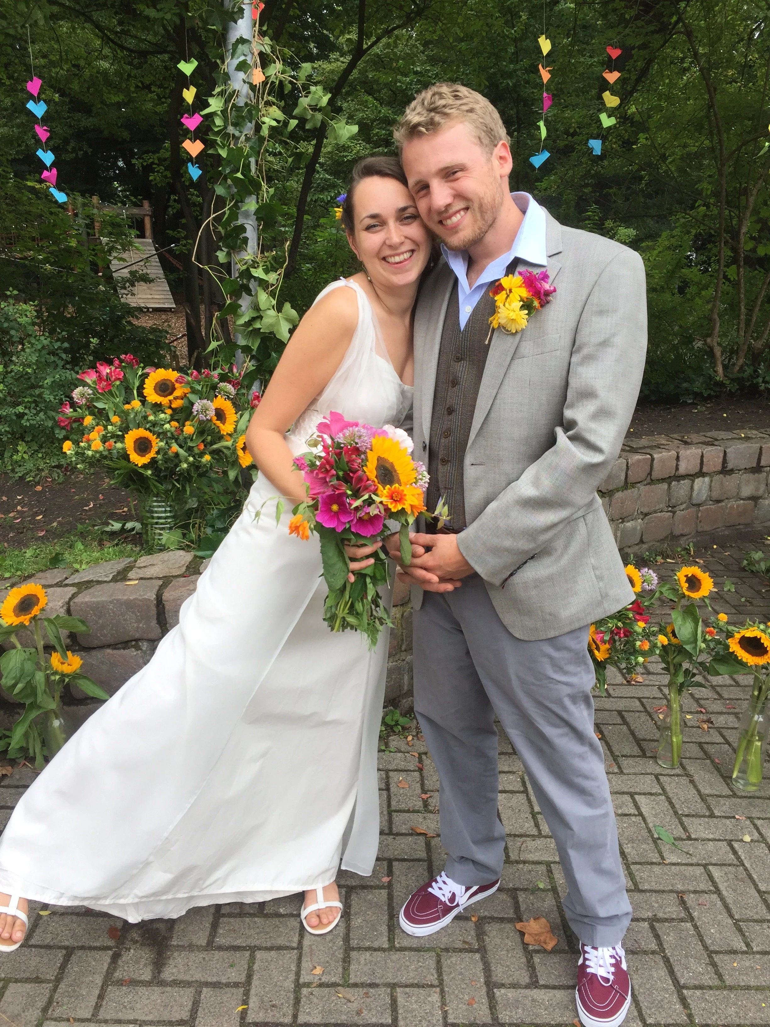 Just married couple smiling. The bride is holding a beautiful colourful bouquet with sunflowers in it.
