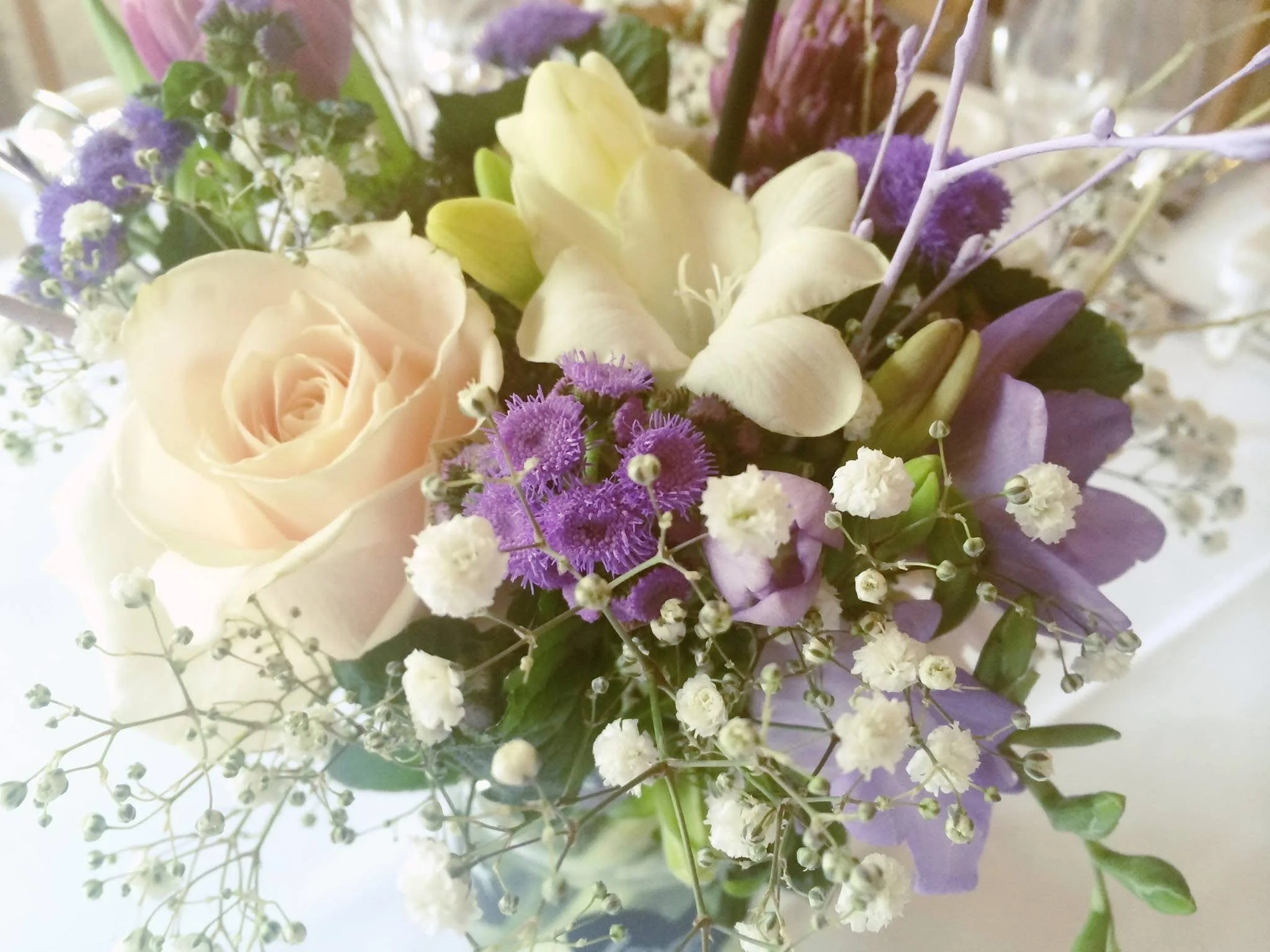 Close-up of a mixed flower bouquet with white roses, purple statice, baby's breath, and other small flowers. Wedding Day.