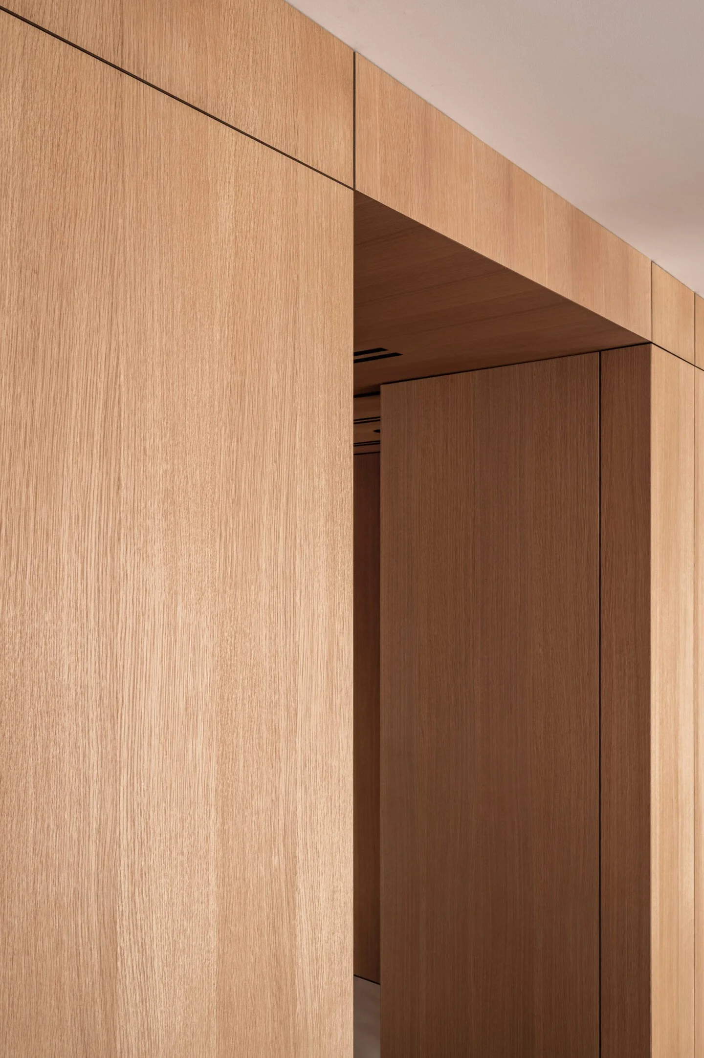Close-up view of wooden interior panels on a wall and ceiling, with a mix of light and dark wood finishes.