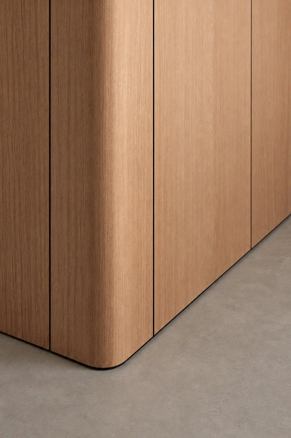 Close-up of a wooden cabinet with vertical panels, curved corner, and a thin black line separating the panels, adjacent to a light gray floor.