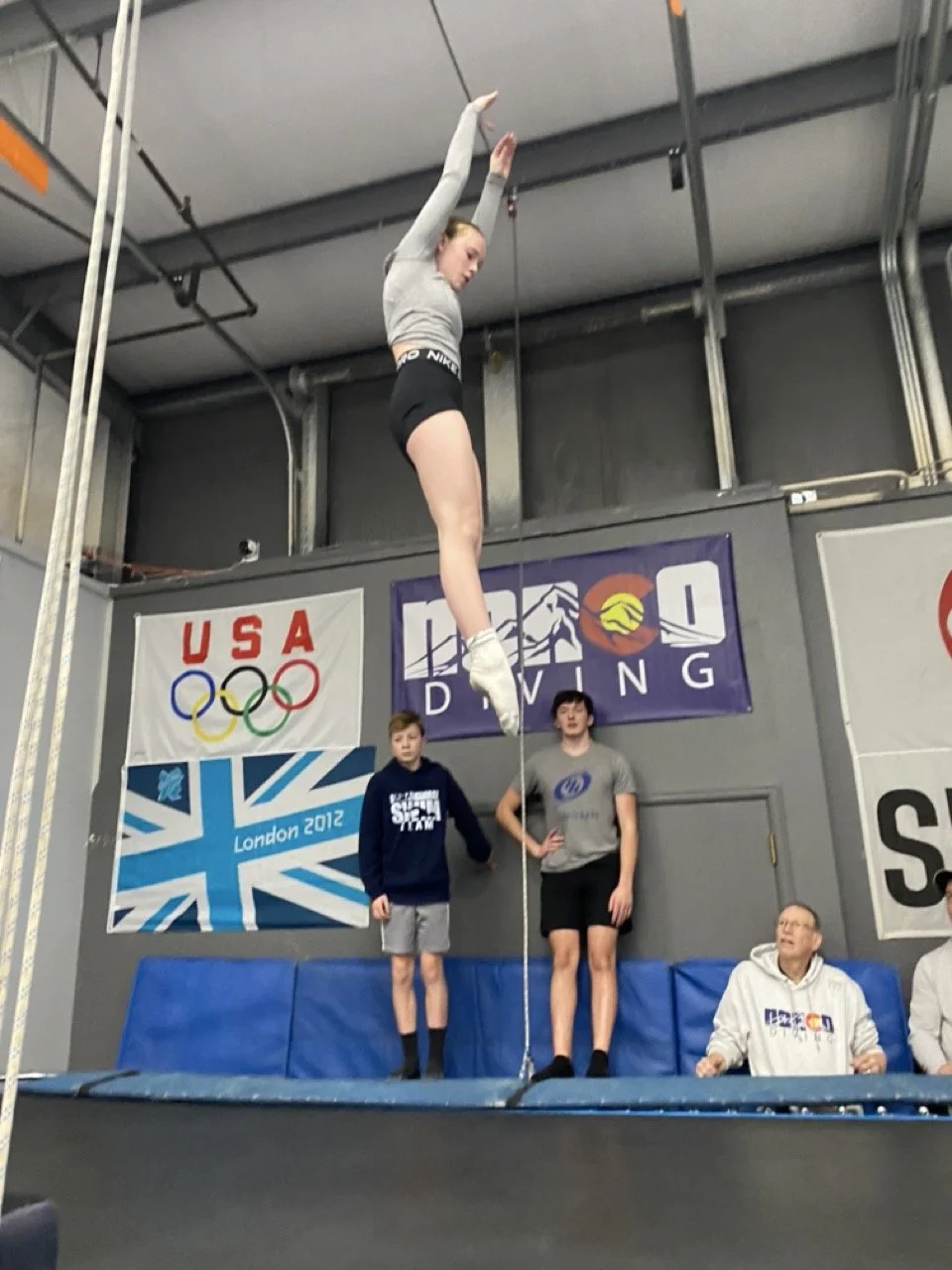 Young athlete flipping on a trampoline with an overhead spotting belt at The Flip Lab