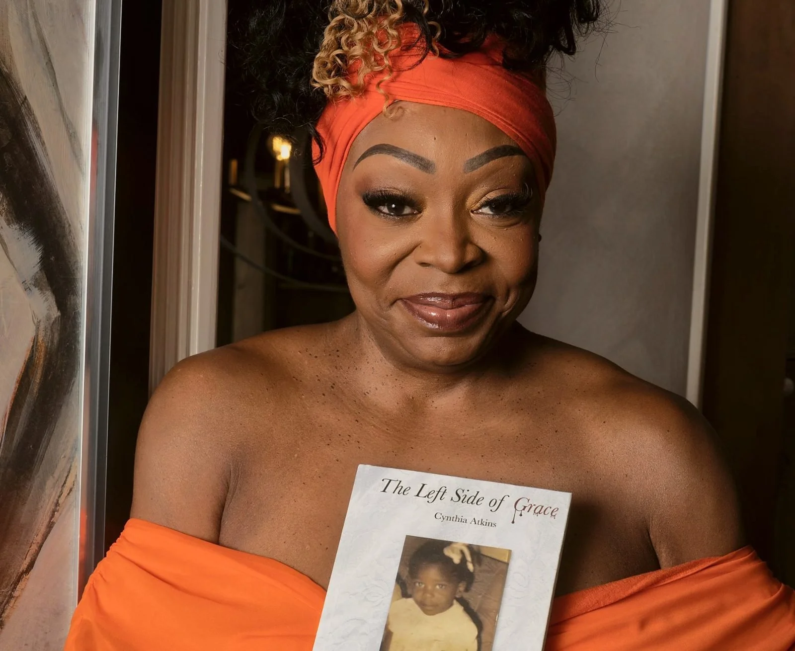 Cynthia Atkins holding her novel, The Left Side of Grace