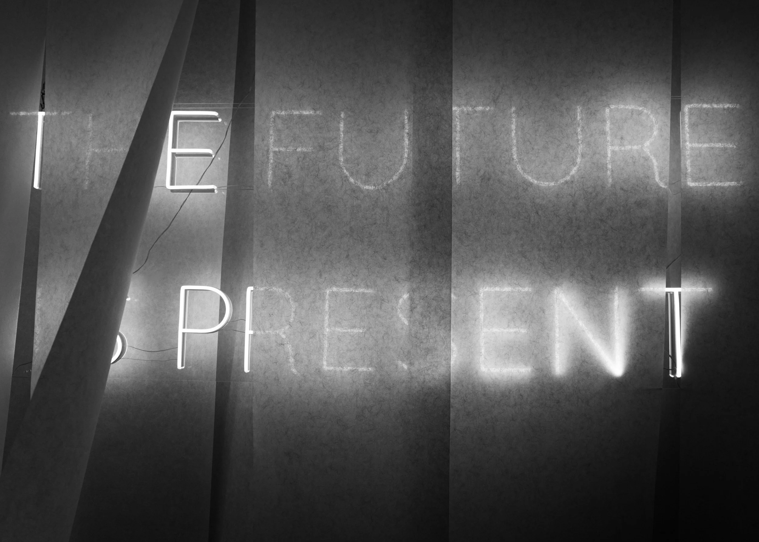 Neon sign displaying the word 'future' in a dark, textured wall with vertical glass panels.