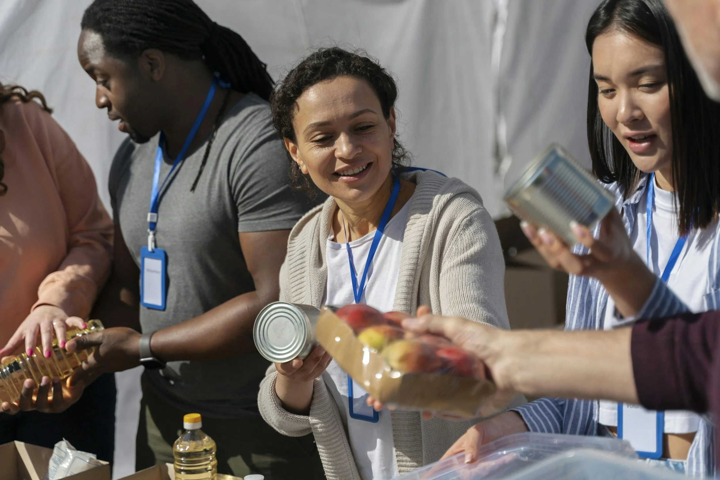 Group of diverse women volunteering at a food drive, sorting canned goods and food items.