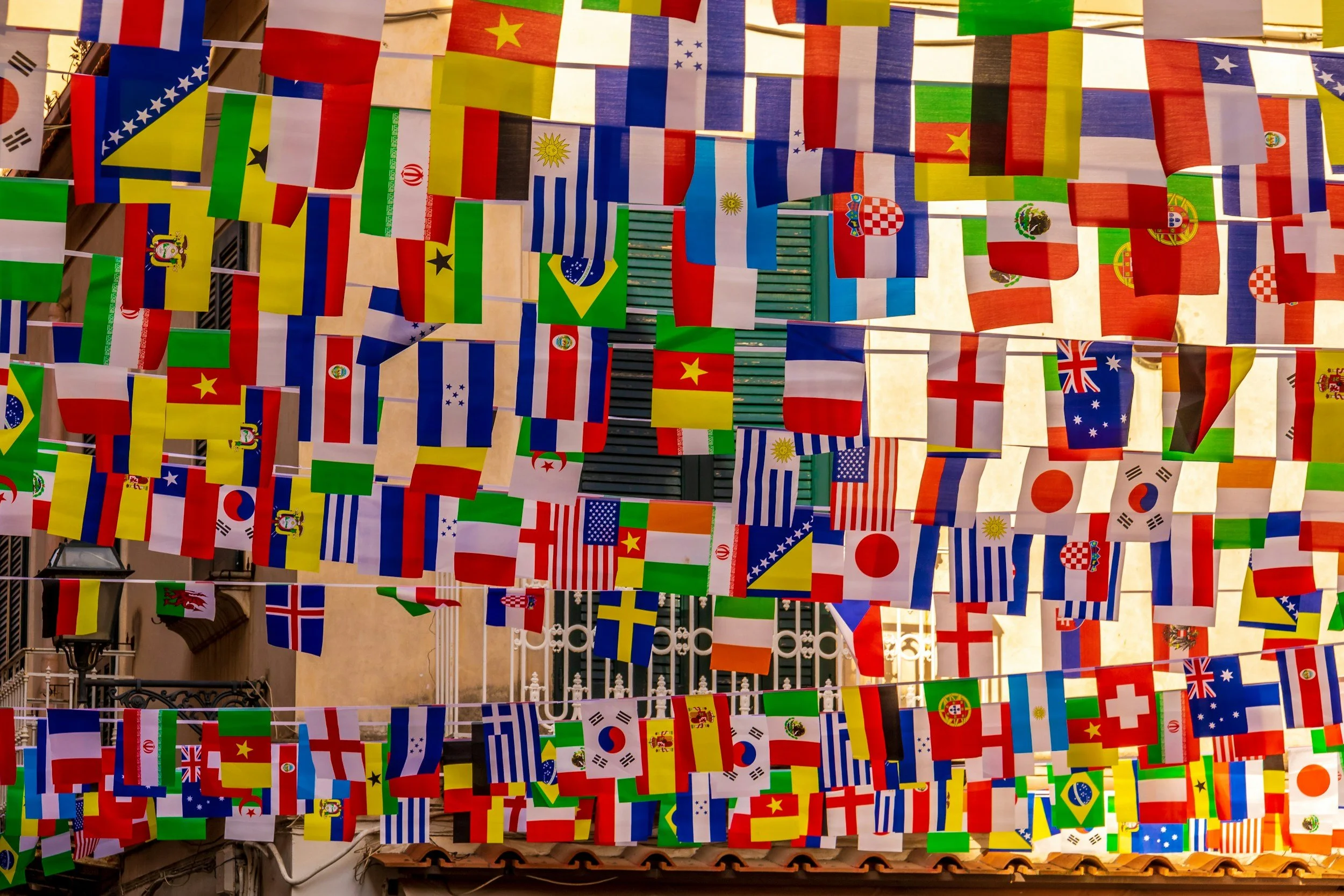 A colorful display of various national flags hanging on strings in an outdoor setting.