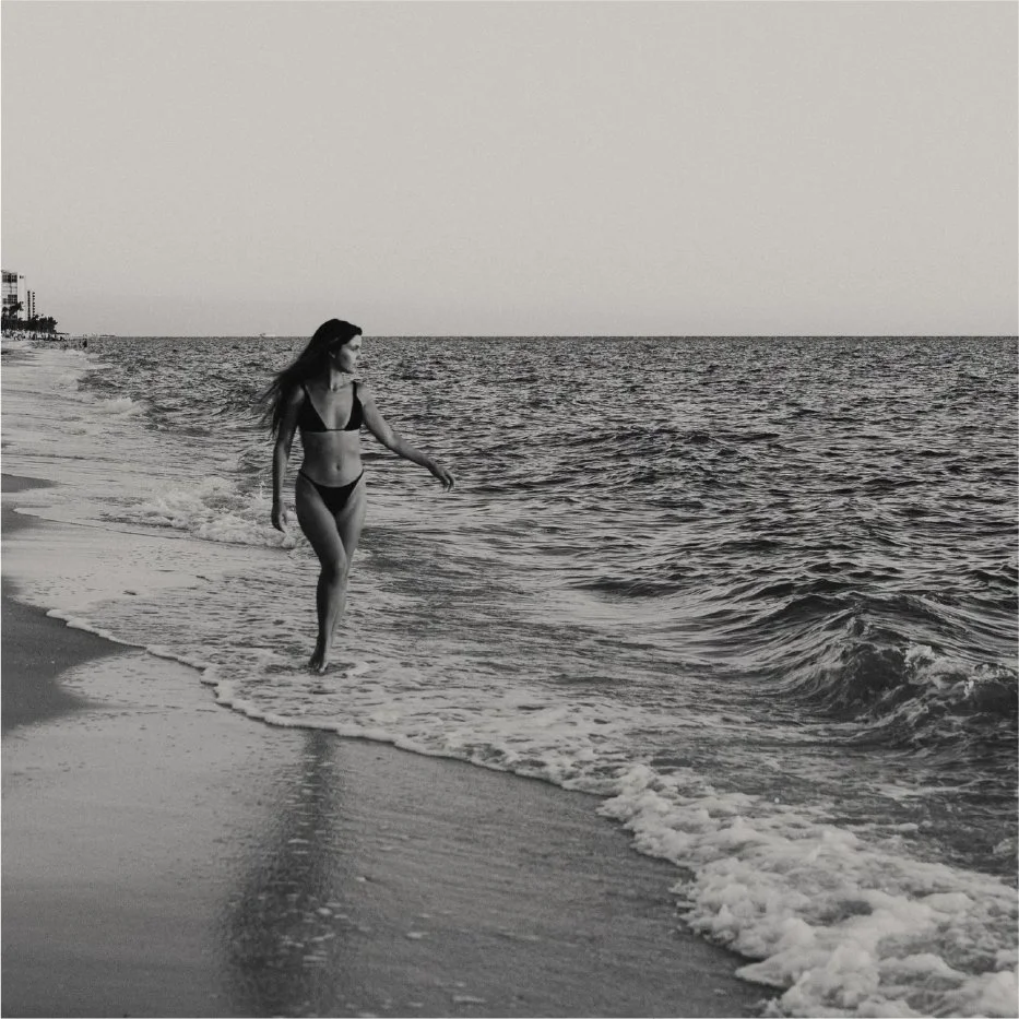 black and white image of woman standing on the shoreline in Naples, , Florida during lifestyle branding session