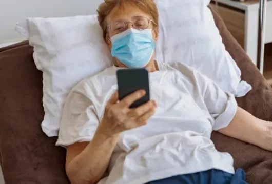 female patient in bed with phone