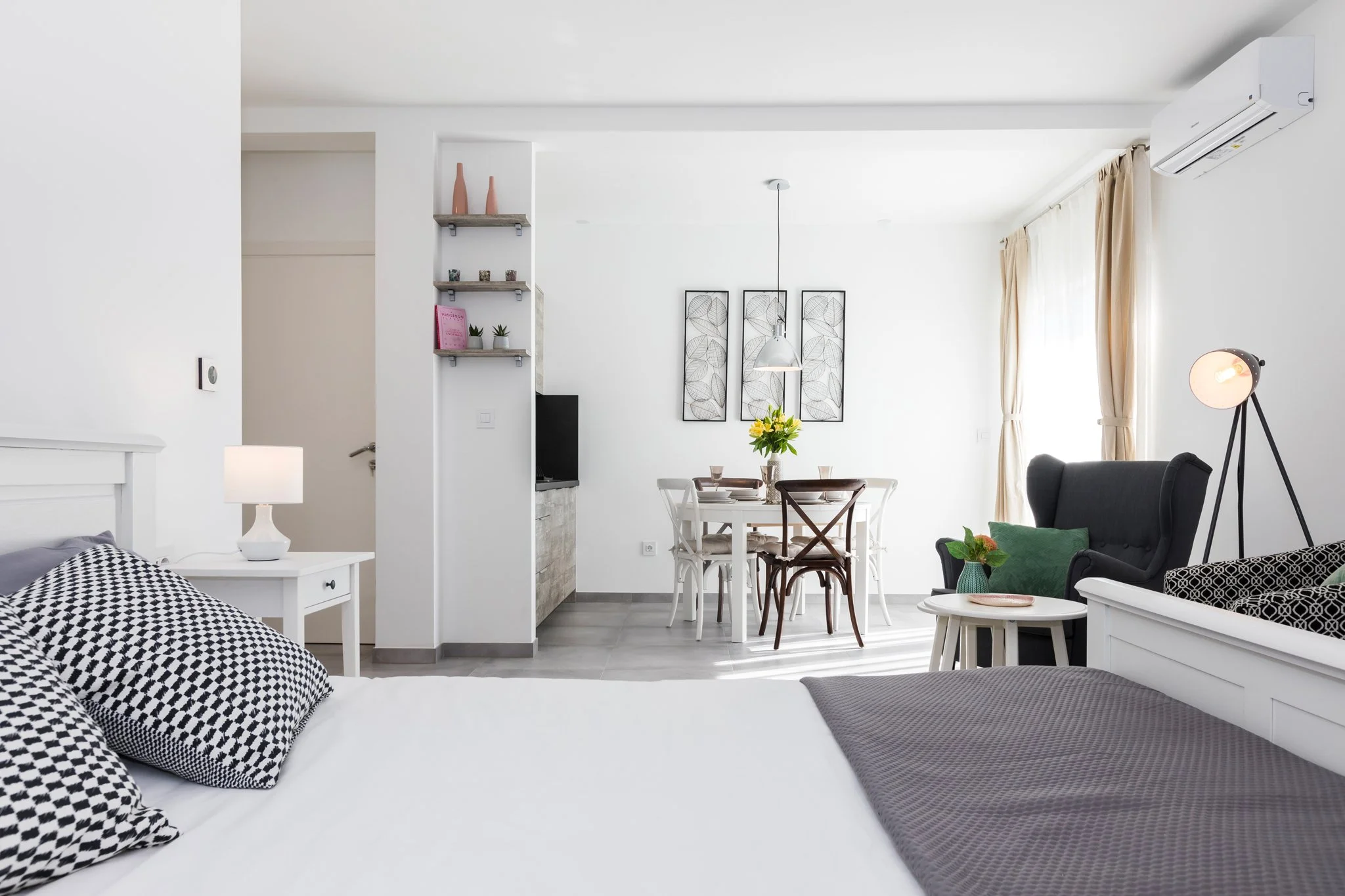 Bright living room with white walls, a dining area, sofa, and decorative wall art.
