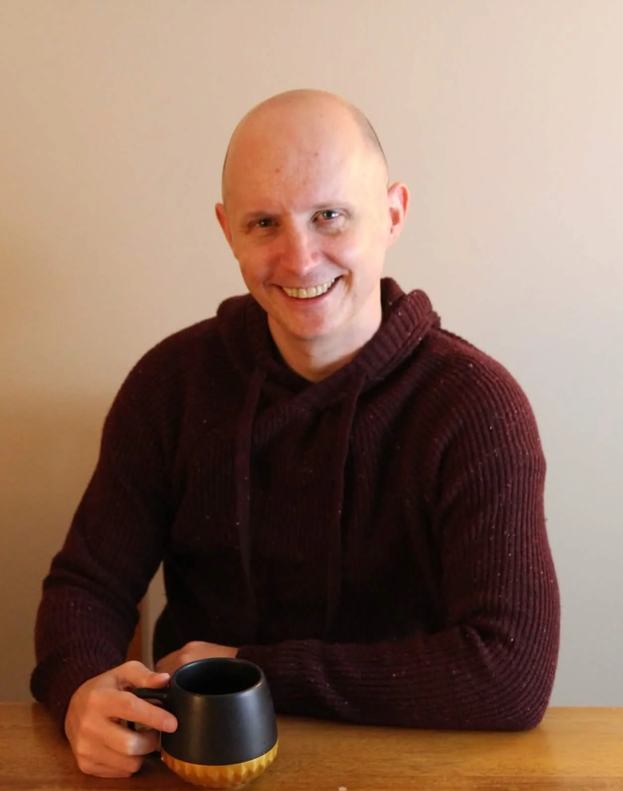 Jordan Redman, licensed therapist and counselor, smiling at a table with a coffee mug