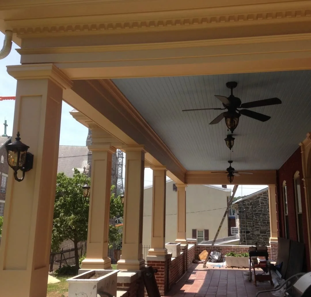 Restored covered porch in Doylestown, PA showing rebuilt columns, detailed trim, ceiling, and finished porch walkway.