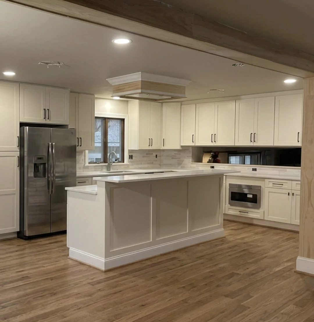 Cream cabinetry kitchen remodel in Pekasie, PA with hardwood flooring, stainless steel appliances, and ceiling hood above island stove top range