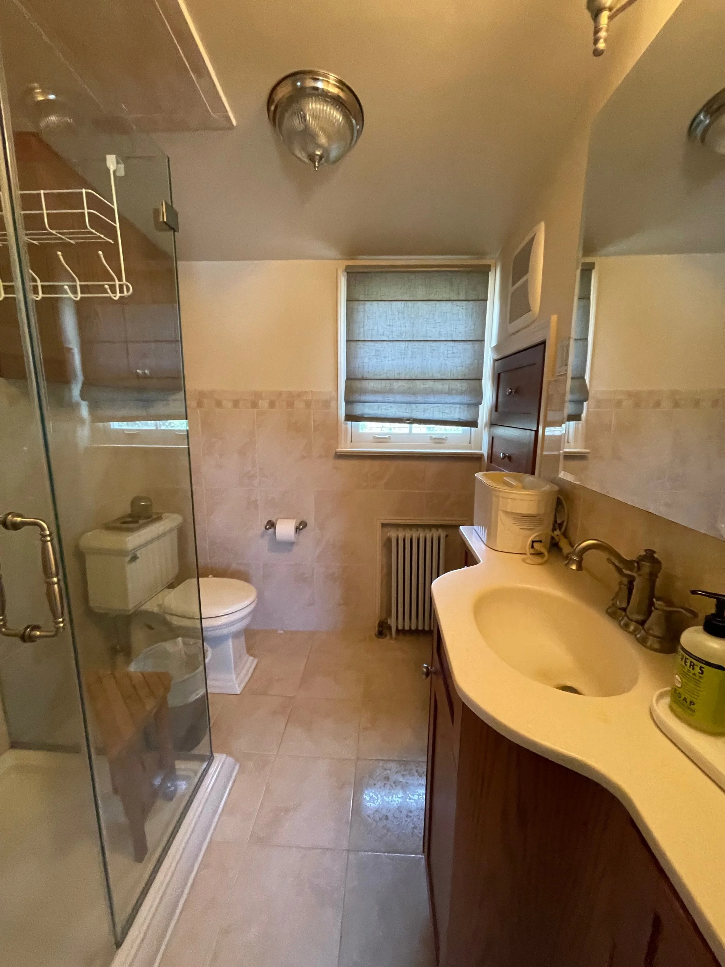 Original tan tile bathroom with toilet, vanity, and window before full bathroom remodel in Hatboro, PA by JWD Contractors